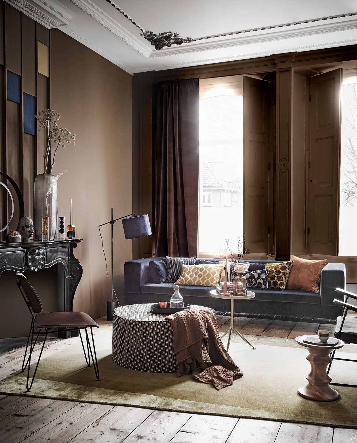 Op de muur, verf per liter: bruine verf Komeet, blauwe verf Ink Blue van Pure &amp; Original, gele verf Luxe S2060-Y10R van Histor (deruamsterdam.nl). Alle stoffen per meter, tenzij anders vermeld: gordijnstof bruin Colour Box velvet f111/11045 (cole-and-son.com). Lampenkap links van de bank van blauw velours-, kussen met fijn dessin van Nobilis-stof, grafische kussens van Designers Guild-stof, kussen helemaal rechts, messing lampvoet (wva.nl). De stof van de poef is Opio van Manuel Canovas (barbaraemmy.com). Bank in blauw velours Loods 5, goudkleurige bijzettafel (loods5.nl). Hoge vaas op de schoorsteenmantel (homestede.nl). Ringvormig object, blauw met amberkleurige kandelaar, blauwe glazen vaas en bruine vaas prijs op aanvraag, bruine glazen pot op goudkleurige tafel, mok op de houten tafel van HK Living, oranje glas op dienblad (loods5.nl). Bruine plaid, zwart dienblad (hm.com). Stoel met leren bekleding (brechtmurreatelier.nl). Vloerkleed, houten kruk van Vitra (covanderhorst.nl). Overige privébezit.