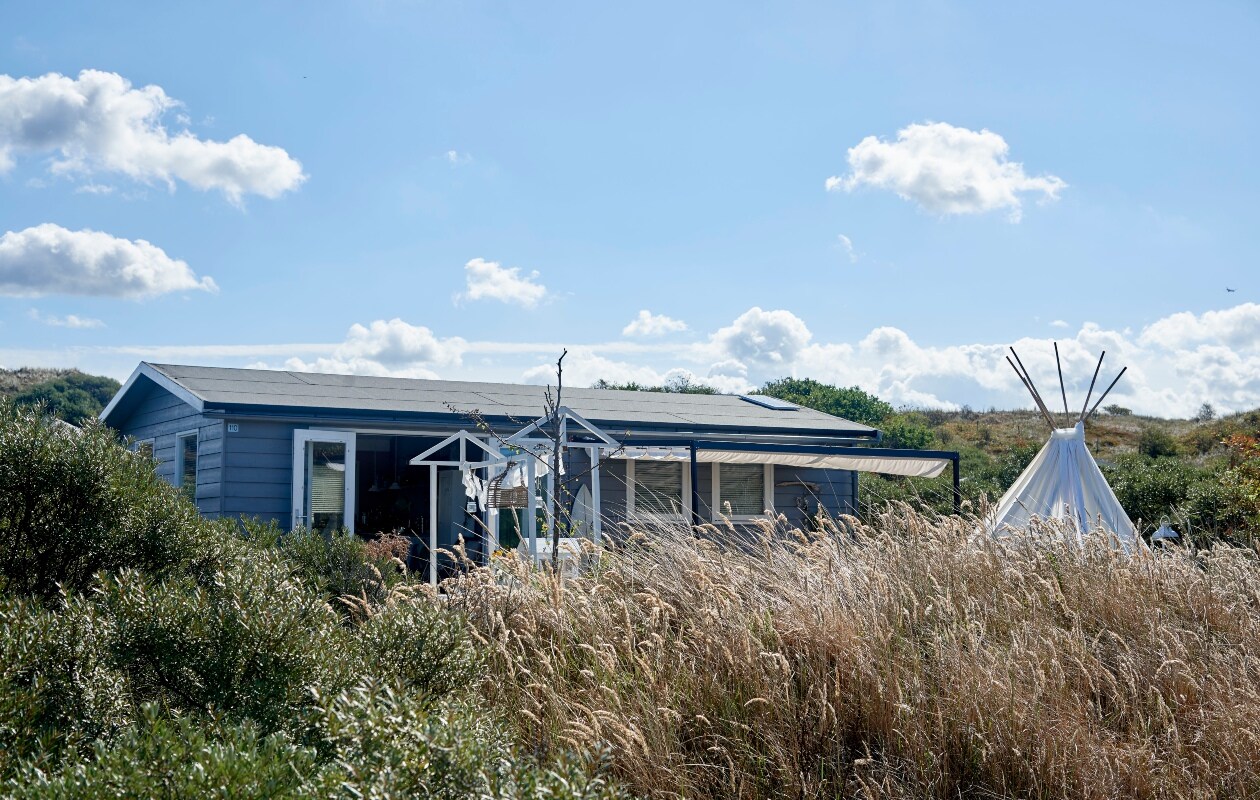 De oude trampoline is nu een chillhoek, met een tipi van bamboestokken en oude Ikea-gordijnen. Gehaakt kleed van Naco, kussens Van Goeden Huize vtwonen bk zomerboek 08-2020 | Fotografie: Renee Frinking