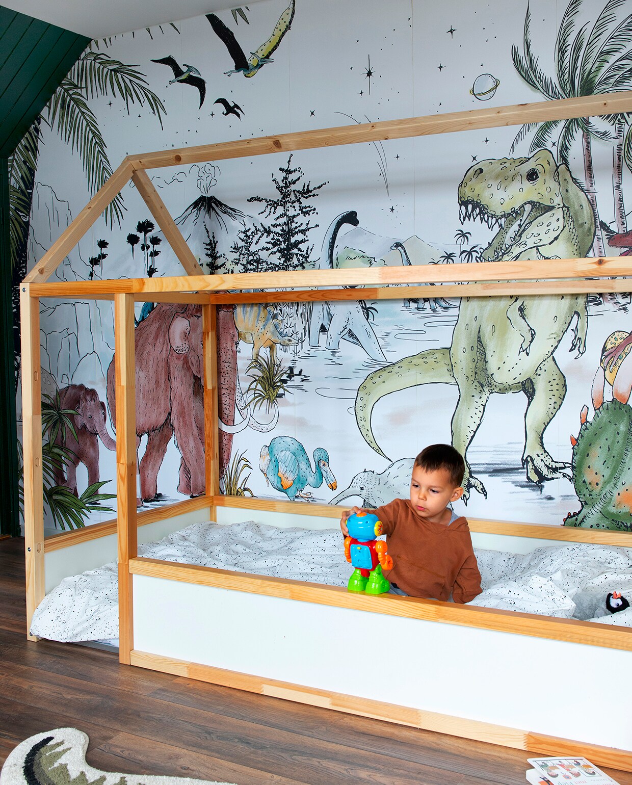 Dino-behang Annet Weelink Design, vloerkleed dino Ginger Roots. Dekbedovertrek Mies &amp; Co, bed met zelfgemaakt dak Ikea. Krat op wielen en houten vlaggenlijn Wibra. Mobile met origami-vogels handgemaakt kraamcadeau. Kledingrek gemaakt door Sofies vader vtwonen 08-2020 | binnenkijken Hillegom