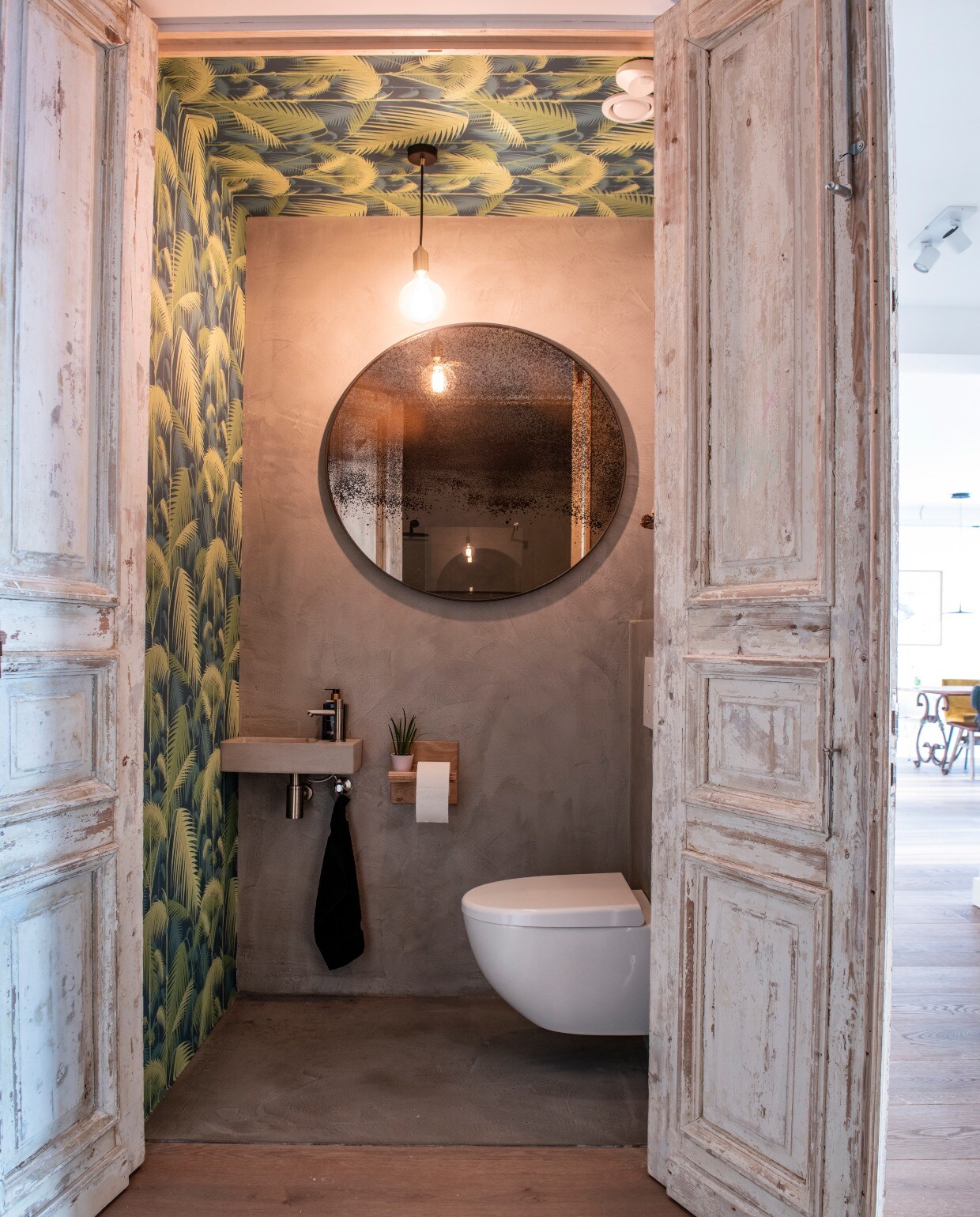 In het toilet werden muur én plafond behangen met behang Palm Jungle van Cole &amp; Son via De Mooiste Muren. Wasbak en kraan Nijhof. Ronde spiegel Notre Monde. Lamp Tala. Toiletpapierhouder Pilat &amp; Pilat. vtwonen bk special 03-2020 | binnenkijken Almere