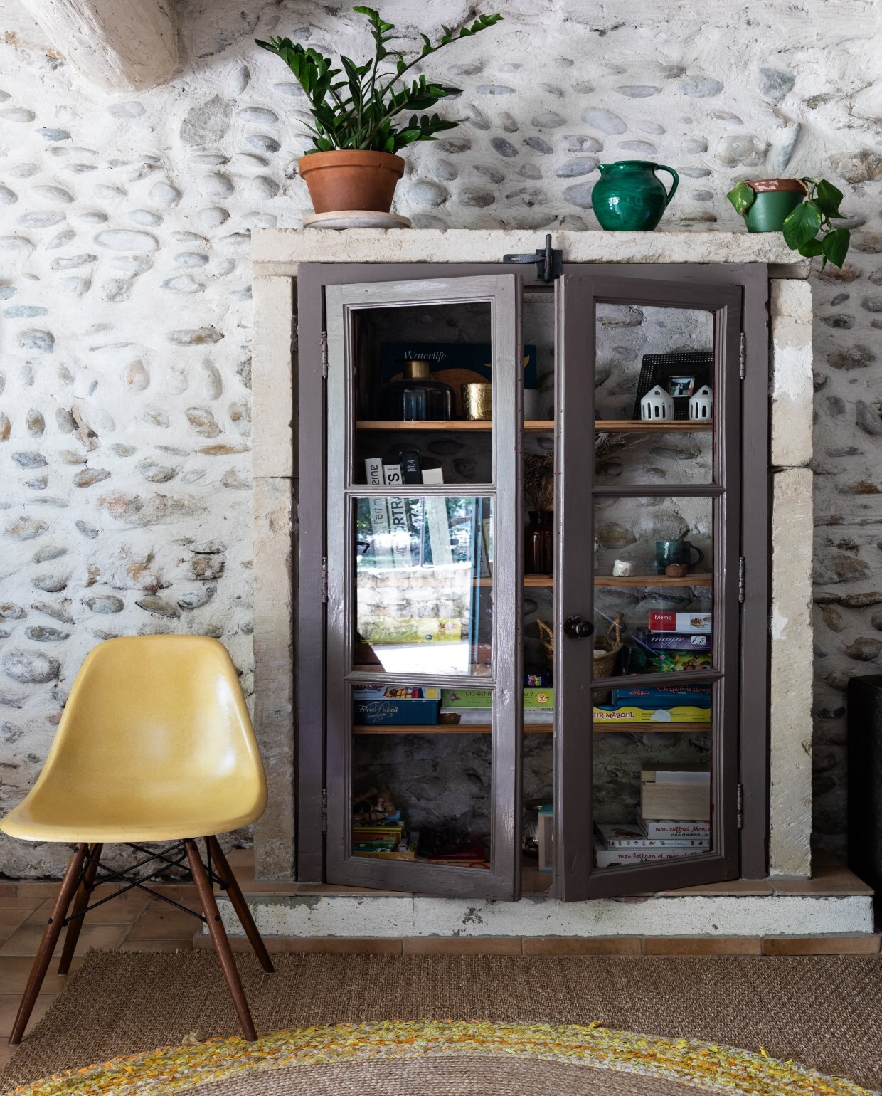 Uniekeinbouwkast, die zowelruimte biedt aan spelletjesvoor de kinderen alswoonvondsten. VintageEames-stoel Vitra. vtwonen 08-2020 | productie Living Inside | fotografie Monica Spezia