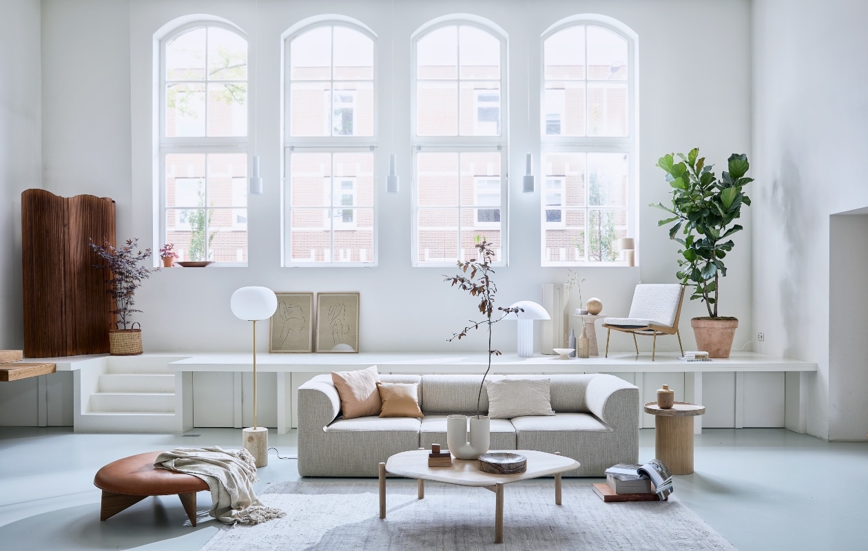 Elementenbank Eave van Menu Space, hoekelement vanaf 86x86x70,5 cm (lxbxh) € 1822,- midden-element vanaf 86x75x70,5 cm (lxbxh) € 1366,-, vloerlamp JWDA van Menu € 1499,95 (designtales.nl). Vloerkleed prijs op aanvraag (misterdesign.nl). Eikenhouten bijzettafel Plateau, 48×52,3 cm (Øxh) € 439,-, wit geoliede eikenhouten salontafel Island, 129x107x35 cm (lxbxh) € 999,-, leren kussen Classic, 40×40 cm € 272,- (bolia.com). Leren poef van Fogia, Ø 112 cm € 1635,-, fauteuil Boomerang van &amp;Tradition, 69x69x80 cm (lxbxh) € 2472,- (kasstoor.nl). Witte u-vormige vaas Kink van Muuto € 179,- (homestede.nl). Bijzettafel Victoria van Zuiver € 279,-, tafellamp Cupola van HKliving € 395,-, marmeren schaal Scapa van Ferm Living € 179,-, fruitschaal van HKliving € 29,-, vaas in zandtint Madam Stoltz € 34,50, langwerpige grijze vaas met handvat van vtwonen € 34,95 (vtwonen.nl). Stukjes hout (fijnhout.nl). Pilaar € 50,- (com-anders.nl). Posters Grace 1 en Grace 11 by lemon met eikenhouten frame, 50×70 cm € 90,- (papercollective.com). Zalmkleurige kussenhoes, 50×50 cm € 9,99 (zarahome.com), linnen kussen, 60×40 cm € 59,- (bymolle.com). Overig privébezit. vtwonen 08-2020 | styling Scandinavisch