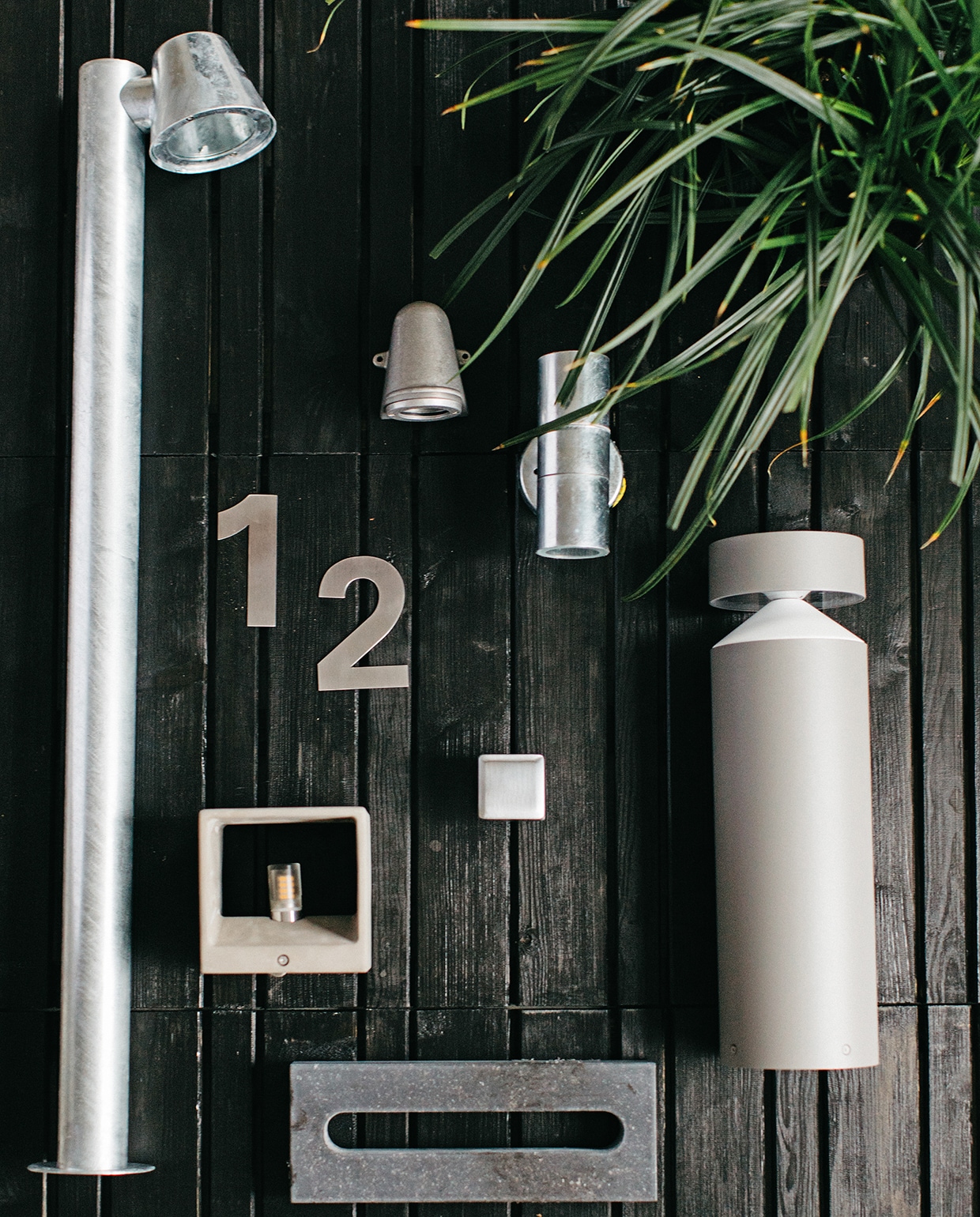 Zwart gebeitste houten vlonders (praxis.nl). Beits van Cetabever (karwei.nl). Rvs buitenbeslag cijfers Jazz, voordeurknop Qbe mat chroom, brievensleuf hardsteen (hardbrass.nl). Gegalvaniseerde staande buitenlamp Konstsmide Trieste, wandlampje Offshore van KS verlichting, gegalvaniseerde up&amp;down spot Konstsmide (fonq.nl). Kubus wandlampje van beton (rietveldlicht.nl). Staande buitenlamp van Eglo (intratuin.nl). vtwonen tuin special 1 2020 | Styling Moniek Visser | Fotografe Danique van Kesteren