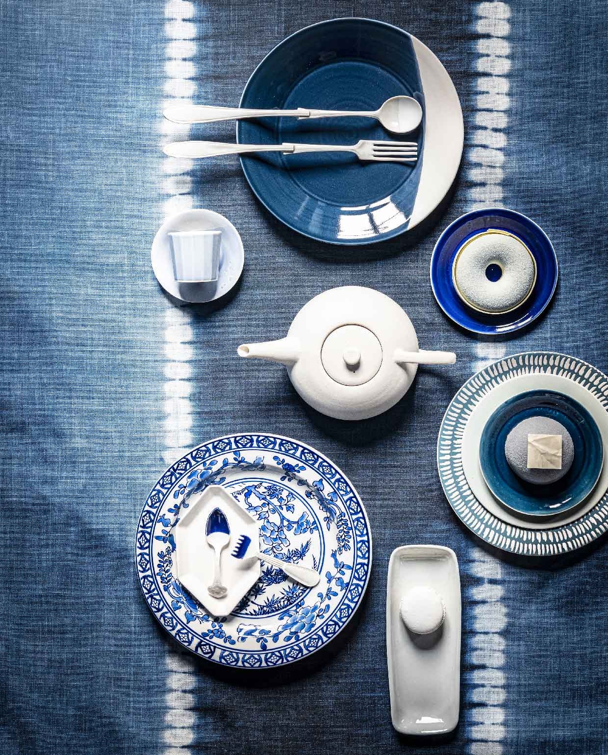 Tafelkleed Ralph Lauren Toc Vers Stripe indigo, per meter € 88,- (wva.nl). Blauw bord met witte rand, prijs op aanvraag (loods5.nl). Espresso kopje met schotel € 46,50, donkerblauw bord met donut, prijs op aanvraag, blauw bord met taartje, prijs op aanvraag (ottomania.nl). Theepot € 224,-. Langwerpig bord, prijs op aanvraag (badenbaden.nl). Blauw bord met streepjes, set van 4 € 56,- (polspotten.nl). Lichtblauw bord € 95,- (frozenfountain.nl). Vork en lepel € 40,-, klein bestek met blauwe rand € 40,-, (lisannevanzanten.nl). Wit hoekig bordje € 10,-, bord met blauwe tekening € 13,95 (hkliving.nl). Taart gemaakt naar wens € 32,95 (huizevanwely.nl). Overig privébezit.