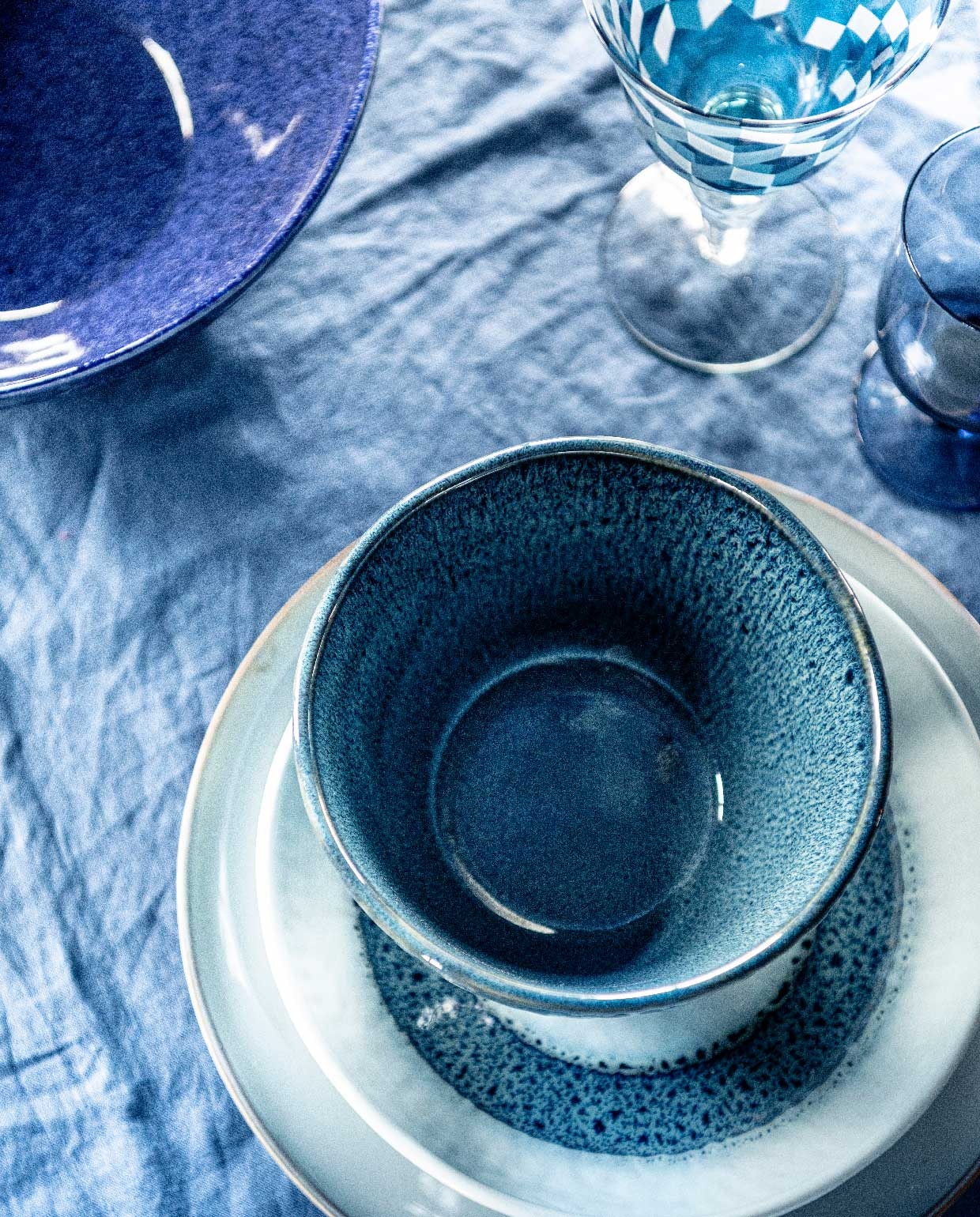 Tafelkleed 145×250 cm € 39,99 (hm.com). Blauwe schaal € 35,99 (zarahome.com). Blauw glas met print, set van 6 € 129,- (polspotten.nl). Onderbord van Leonardo, Ø 27 cm € 12,95, bord van Leonardo, Ø 23 cm € 9,95, kom van Leonardo, Ø 15 cm € 9,95 (vtwonen.nl). Blauw wijnglas € 8,95 (loods5.nl).