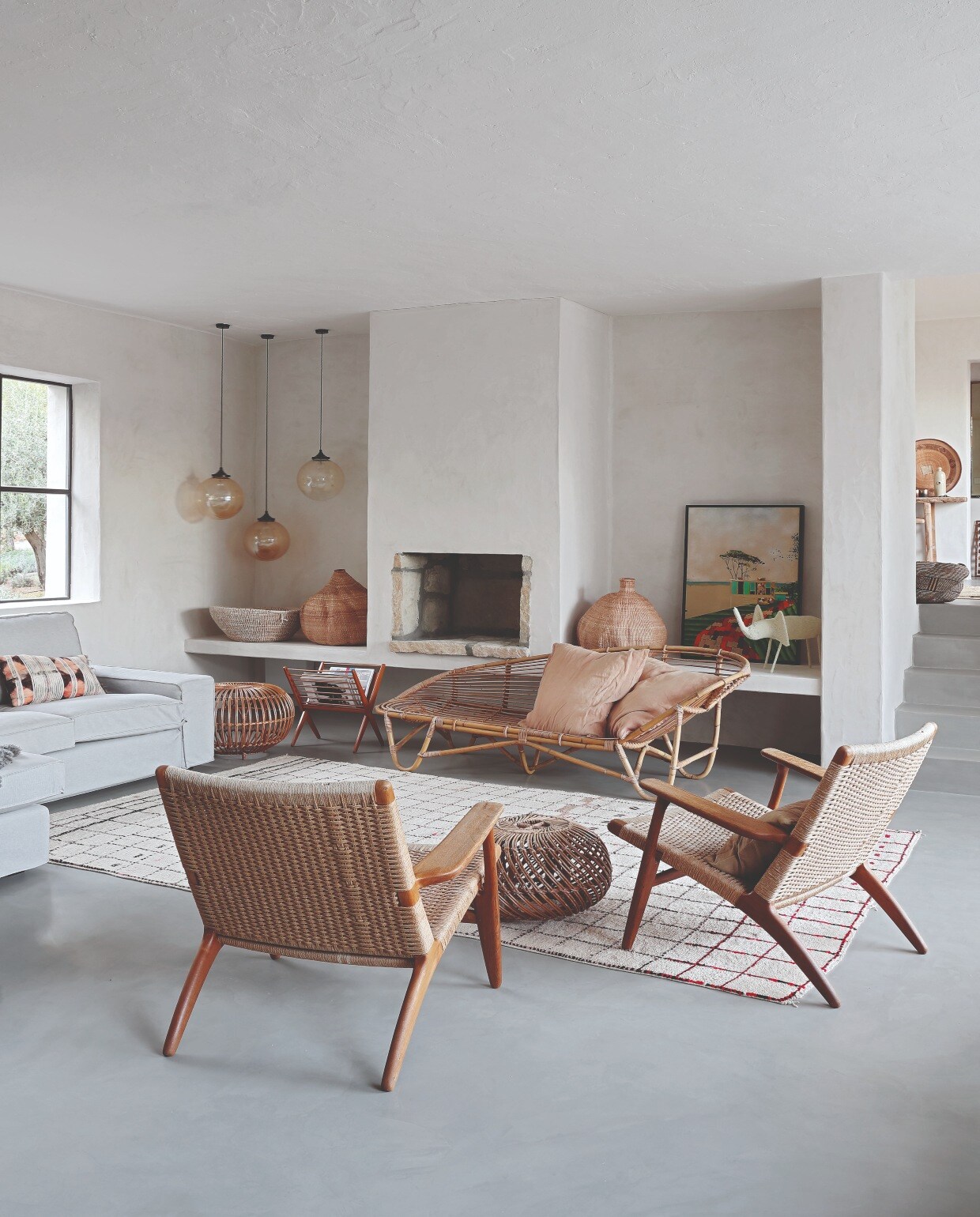 Hanglampen Retrouvius, Hans J. Wegner stoelen van Mid Century Antiques, beide in Londen. Rotan bank Homeplace, Berber vloerkleed uit Marokko. Grijze bank Ikea, schapenvachten The Organic Sheep. Schilderij van de Australische kunstenaar William Mackinnon vtwonen 07-2020 binnenkijken ibiza