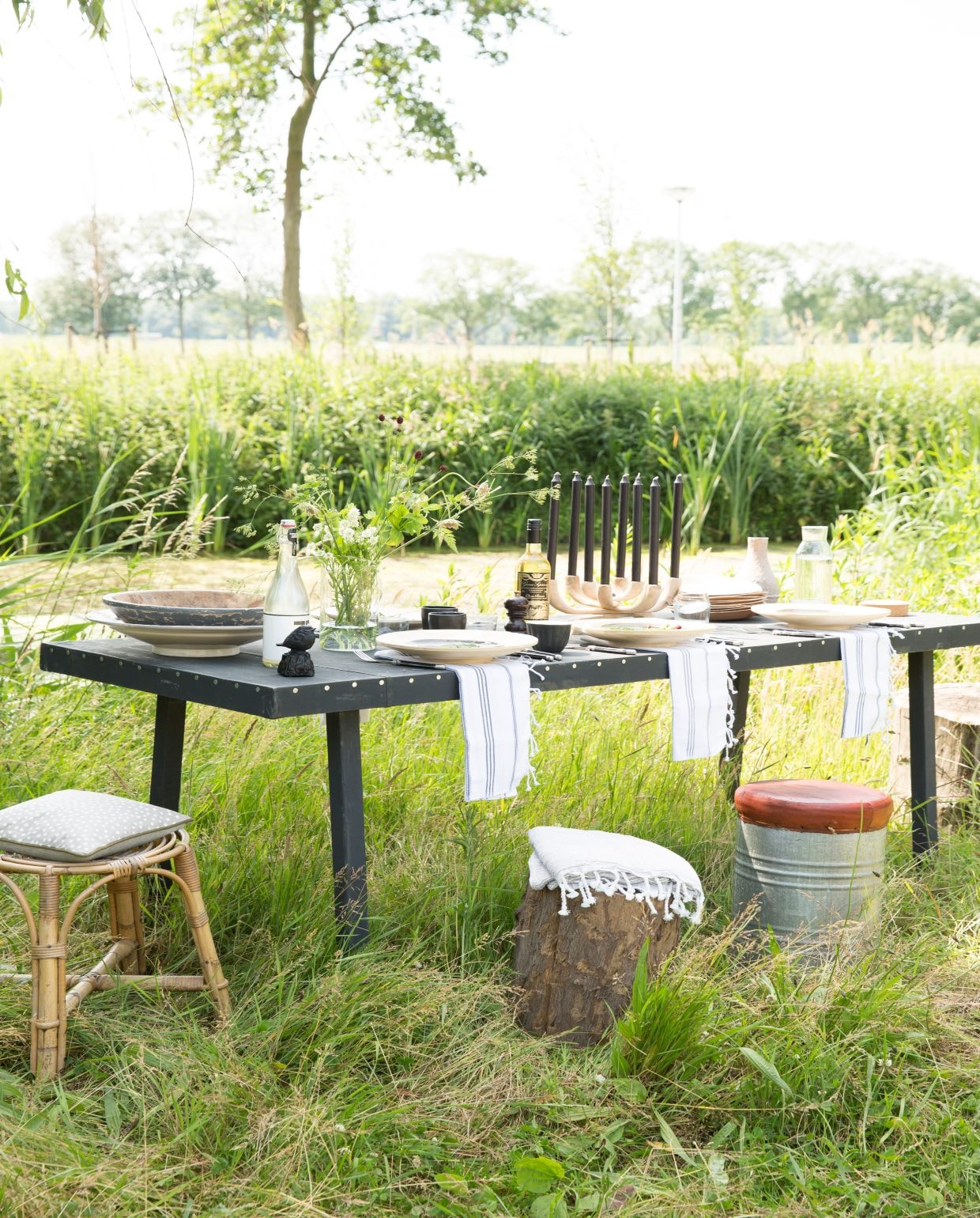 Tafel van Combitex prijs op aanvraag (www.com-anders.nl). Boomstammetje (www.nijhofbaarn.nl). Kruk van oud blik met leren zitting (www.debongerd.nl). Servetten (www.ottomania.com). Bamboe bordjes, Ø 30 cm, glazen, per 6, glazen karaf met kurk (www.ikea.com). Siroop van Nicolas Vahé (www.tierlantijn.net). Zwarte koffiebeker (www.polspotten.com). Bestek van LaGuiole, 24-delig, houten kandelaar, kaarsen (www.andersnog-iets.nl). Bamboe kruk, bordjes en beker (kringloopwinkel). 04-2017 | vtwonen tuin