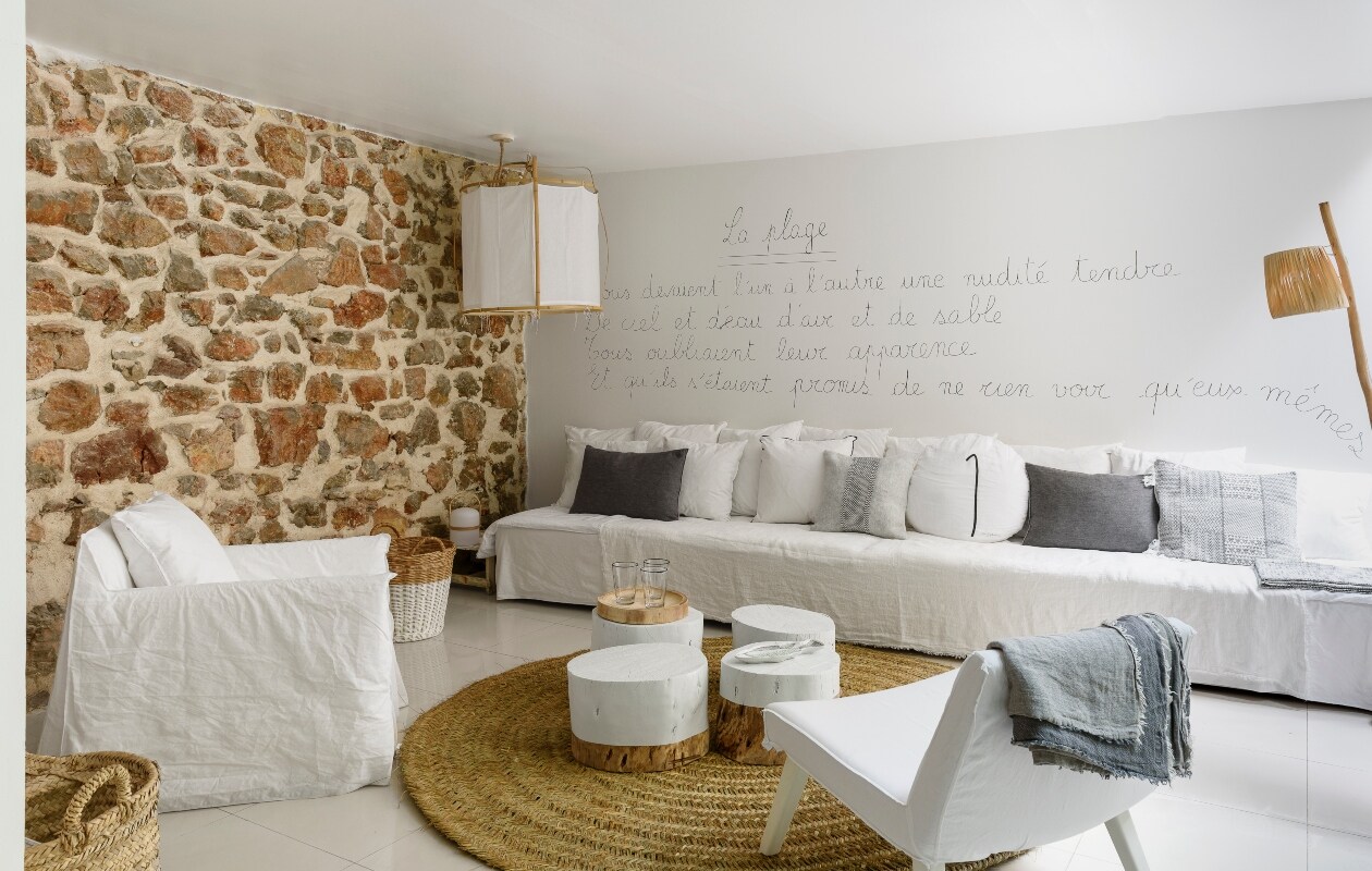 Patricia schreef zelf het gedicht La Plage van Paul Éluard op de muur. De lange bank is op maat gemaakt. Hanglamp Serax, vloerkleed Le Nouveau Décoration, de salontafeltjes zijn handgemaakt vtwonen 07-2020 | binnenkijken cannes strandhuis