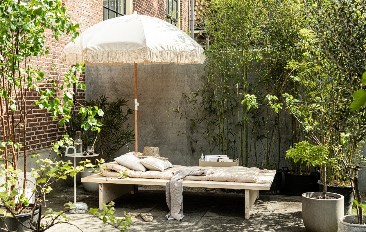 Parasol Dunes € 274,95 (sundaysupply.co). Matraskussen € 69,99, linnen kussens vanaf € 22,99 (zarahome.com). Strohoed € 35,-, zonnebril € 15,-, gevlochten slippers € 69,- (stories.com). Badlaken € 14,99, glazen € 14,99 (hm.com). Bijzettafel Bowler van Hay € 215,-, metalen box van Ferm Living in kleur Cashmere € 65,-, geribbeld glas van Ferm Living, per 4 € 39,- (vtwonen.nl). vtwonen 06-2020 | DIY zomers ligbed