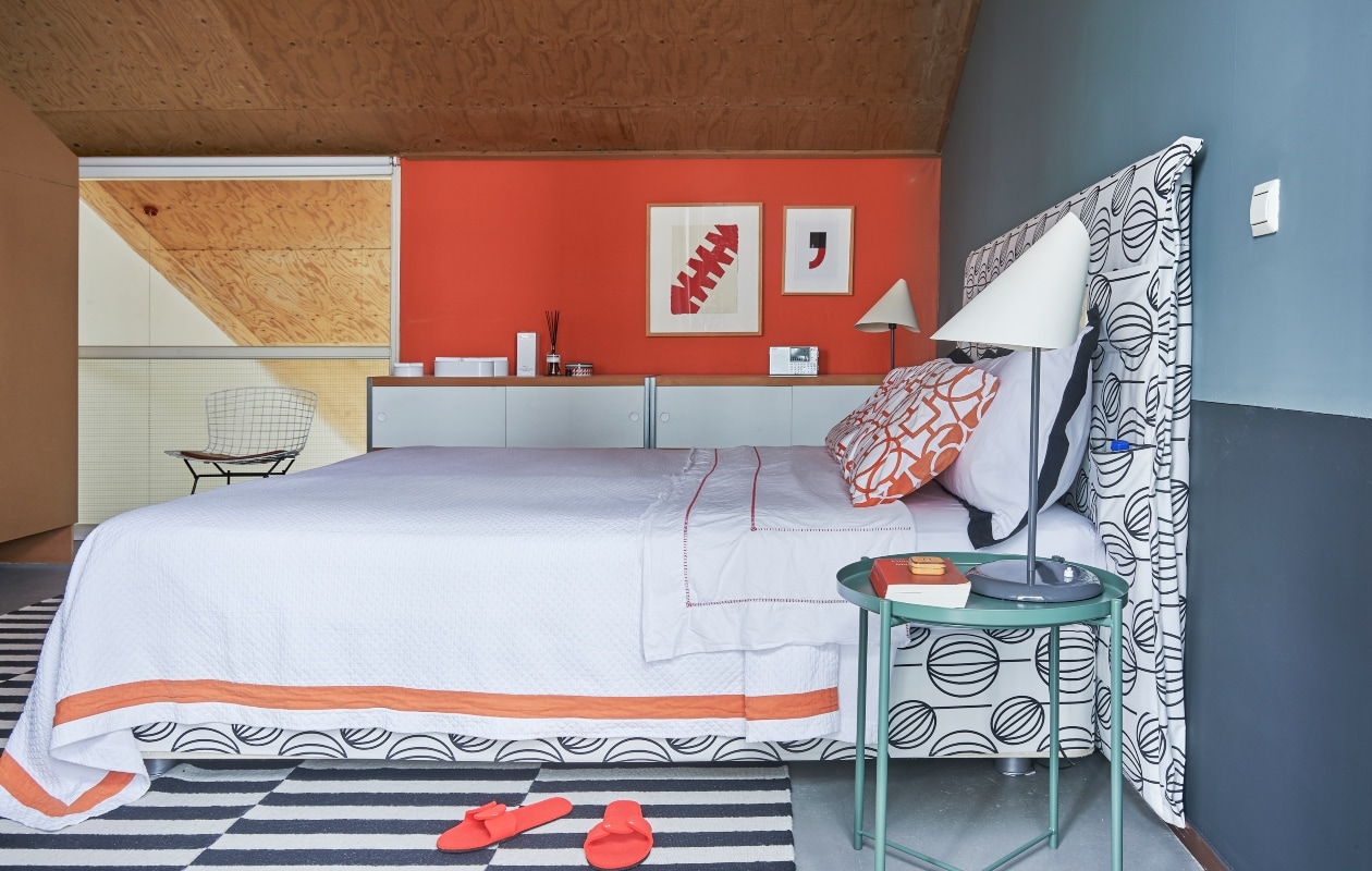 Bed Vispring, bekleed met stof van Ikea. Kussens Zara Home. Tafeltje en vloerkleed Ikea, tafellampen Sirrah. Muurkunst van El Gato en een onbekende kunstenaar (de komma). Kasten Kewlox. vtwonen special binnenkijken 03-2020 | styling Rob Jansen | fotografie Dennis Brandsma