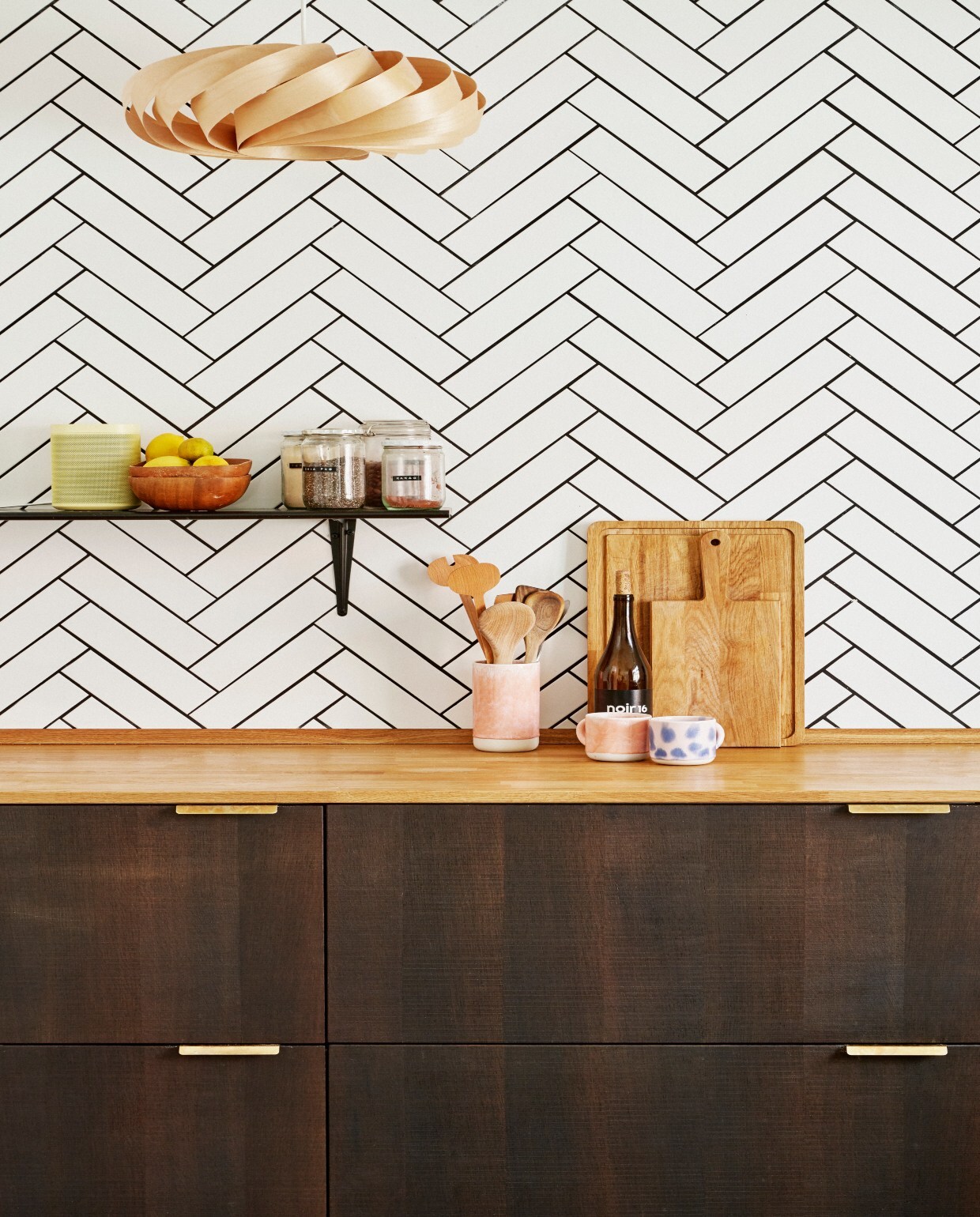 Standaard Ikea-keuken met eikenhouten fronten, aanrechtblad en koperen handgrepen van Reform. Kraan Vola. Tegels Mosaikhjørnet, gelegd in een visgraatpatroon met zwarte voegen. Berkenfineer lampen Tom Rossau. vtwonen 06-2020 | twee-onder-een-kapwoning Denemarken