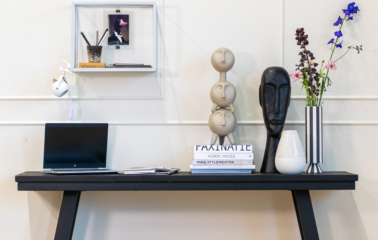 Houten sidetable Corti van Light &amp; Living. Metalen rek vtwonen. Klemlamp Bastia van Trio Lighting. Ecomix ornament Faces van Urban Nature Culture. Houten ornament Headman XL van Be Pure Home. Gestreepte keramieken vaas Toppu van Oyoy.  Kunststof kruk Dover van Woood (vtwonen.nl/shop). Overig privébezit. vtwonen 2024-02 | styling Fietje Bruijn | fotografie Lotte Kwant