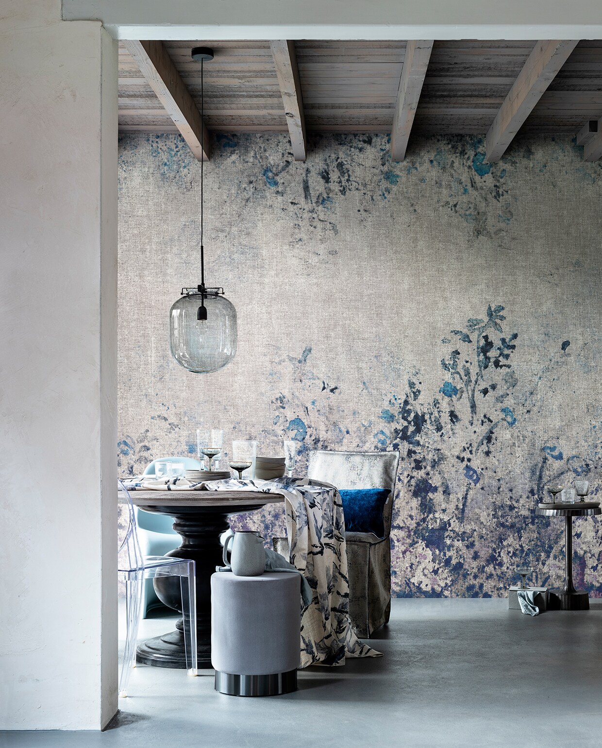 Behang Play with me van LondonArt (linkitalia.nl). Bijzettafel (polspotten.nl). Grijs wijnglas (sostrenegrene.com). Grijze champagneglazen (klevering.nl). Grijs doosje (loods5.nl). Eettafel, 77×120 cm (hxø) (pureblacklabel.com). Blauwgrijze fluwelen poef van Tenzo, 45×34 cm (hxø) grijze kommen, en grijze borden van Bloomingville, champagneglazen, glazen kan, waterglazen, alles van Serax, grijze kan, rookglazen hanglamp van House Doctor (vtwonen.nl). Tafelkleed gemaakt van stof Shangri-La Lino in kleur Graphite van Designers Guild, kussenhoes van stof Velluto in kleur Cobalt van Designers Guild (wva.nl). Stoelhoes van stof Olinda 7703-2, (eijffinger.com). Lichtblauwe stoel, transparante stoel (loods5.nl/design). Linnen servetten (hm.com). vtwonen 03-2020 stof verf &amp; behang | eetkamer met bloemenbehang en glazen hanglamp