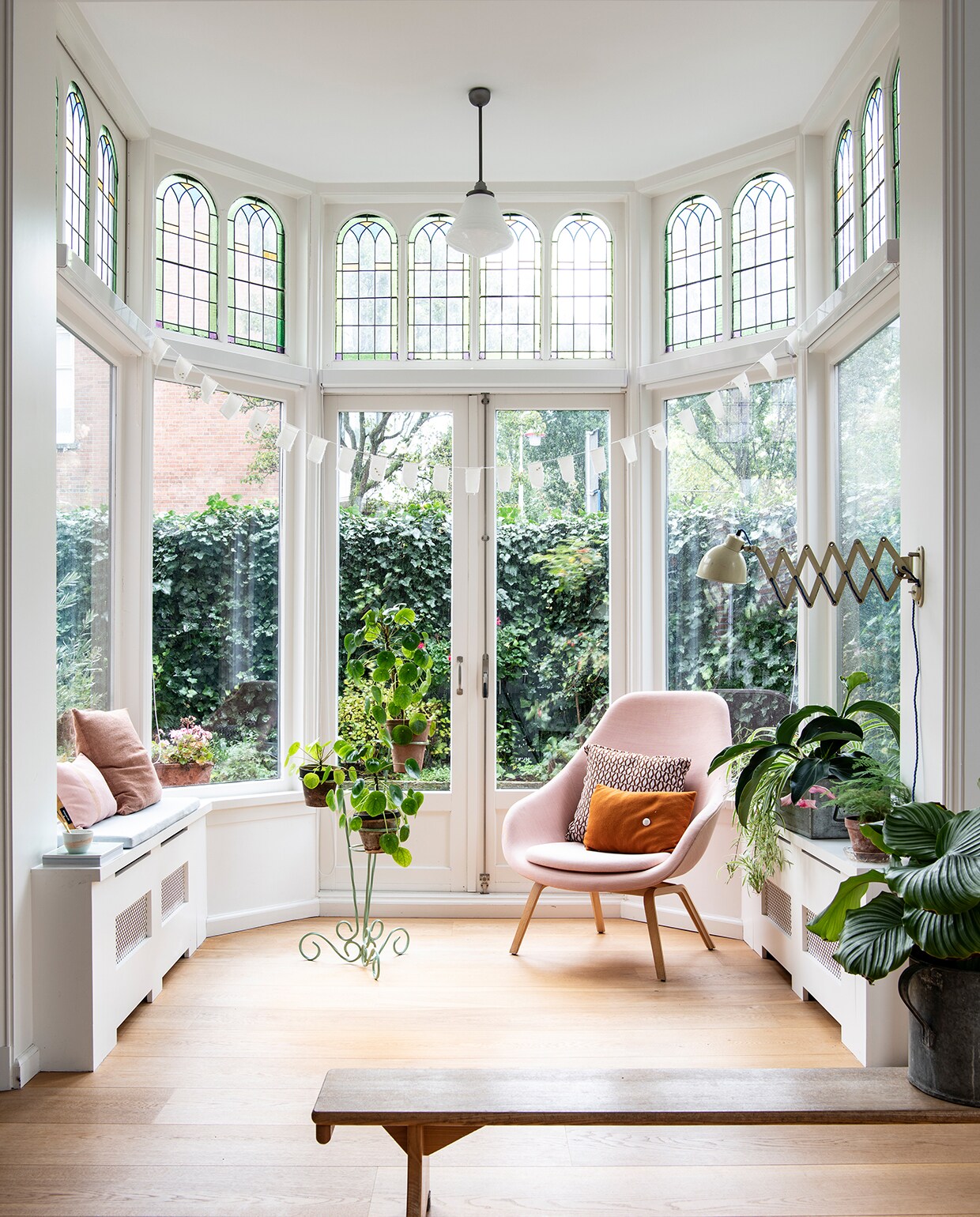 Fauteuil Hay, bruin kussen Tas-ka, grafisch kussen Karwei. Plantenstandaard uit Frankrijk. Schaarlamp gevonden op de Koninginnedagvrijmarkt. Slinger zelfgemaakt. Houten bank op straat gevonden. Kussens op kast: roze Fest Amsterdam, bruin Karwei. Radiatorombouw op maat gemaakt door Steengoed Partners. De hanglamp hoorde bij de boedel van een vorig huis en werd meegenomen als aandenken.