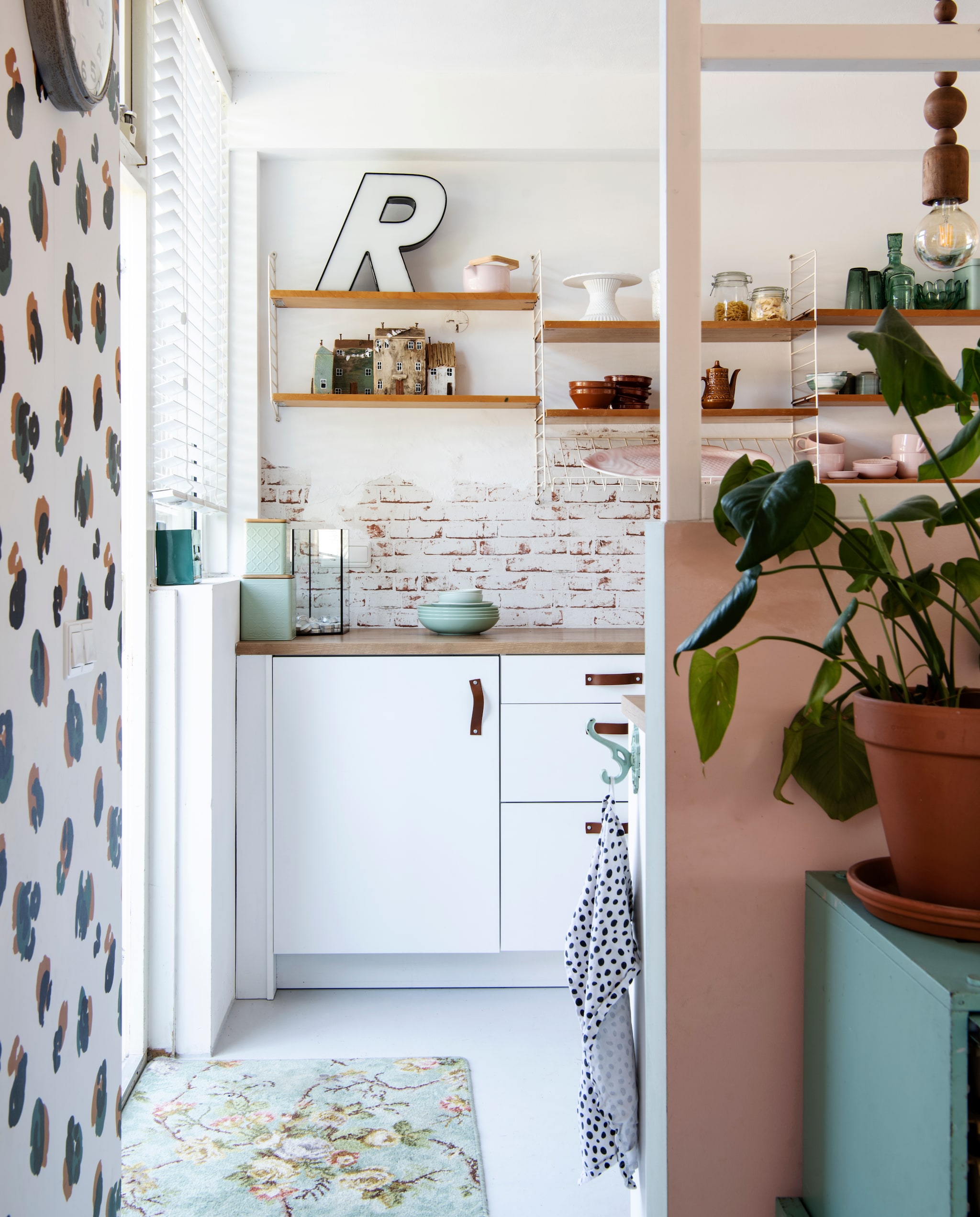 Behang met baksteenpatroon van Hornbach. Wandrek van String Pocket. Groene bewaardoosjes van Xenos. De letter R is een vintage vondst.