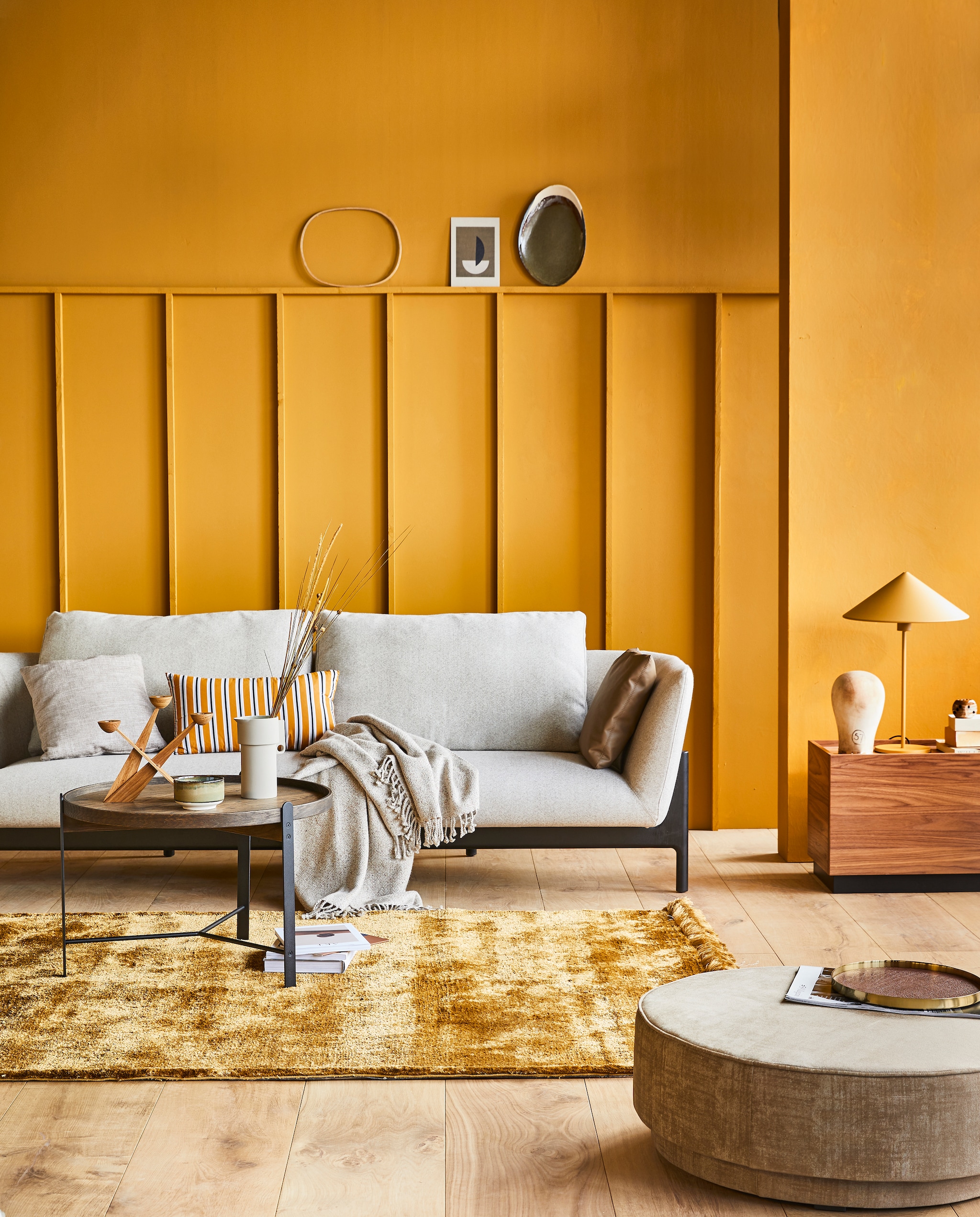 Muurverf DesertM.m.v. design020.nl (bank van Bensen), goeds.nl (salontafel), restored.nl (grijze porseleinen kan), &amp;klevering.nl (kandelaar), vtwonen.nl (gele tafellamp Triangle van HKliving, vloerkleed Nami van Bolia, gestreept kussen van Normann Copenhagen, plaid van Kaat Amsterdam, bijzettafel Block en ronde poef Pearl uit de vtwonen collectie), vandijkenko.nl (hoofd), casagitane.com (bord), hm.com (dienblad). vtwonen 04-2020