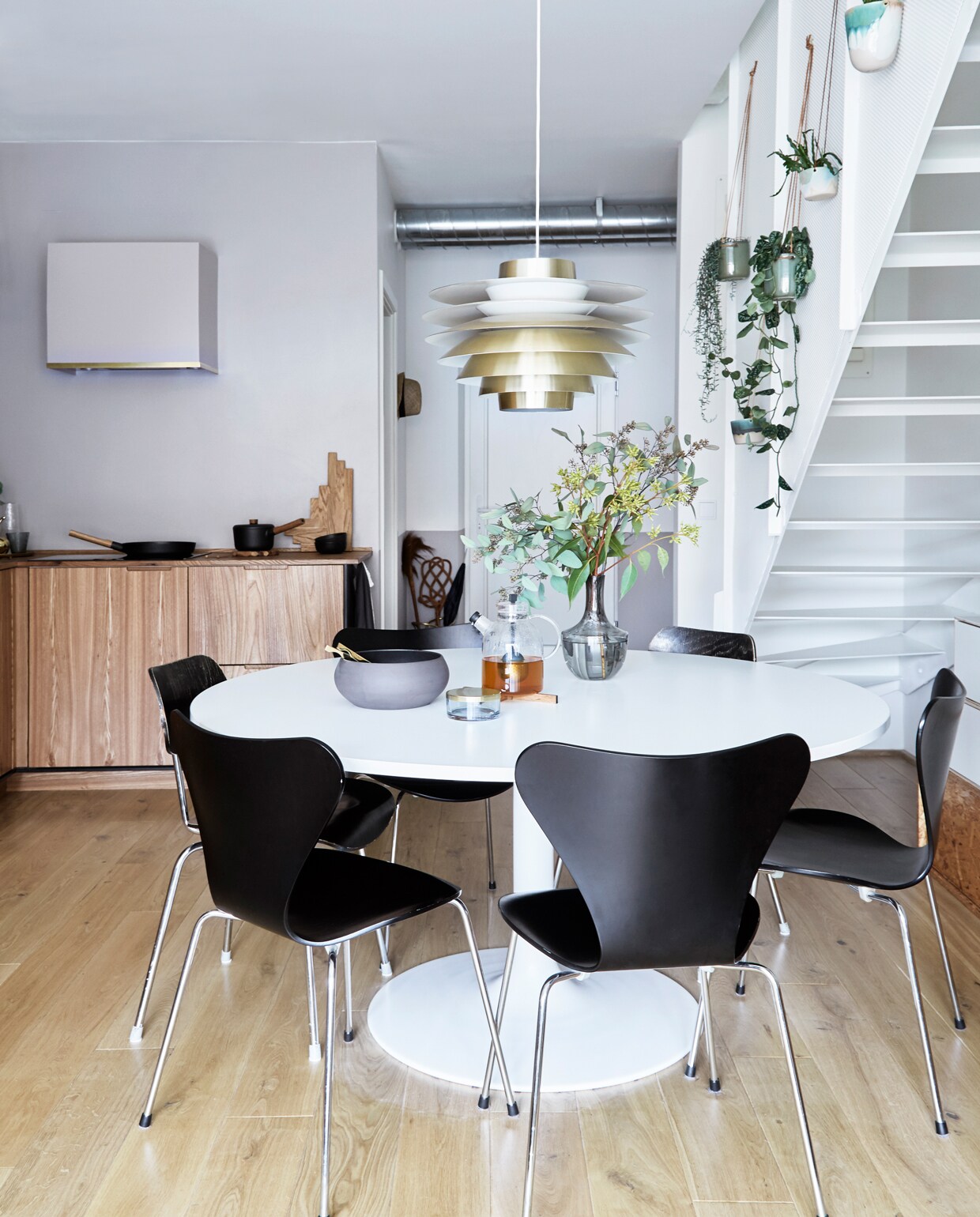 De eettafel is een ontwerp van Ejvind A. Johansson, hanglamp Verona van Svend Middelboe gekocht bij Lysfabrikken. Stoelen Fritz Hansen. Lamp Lysfabrikken. Theepot Menu, onderzetter Skagerak, kom Ro Collection, glazen potje Aytm, vaas Ikea.