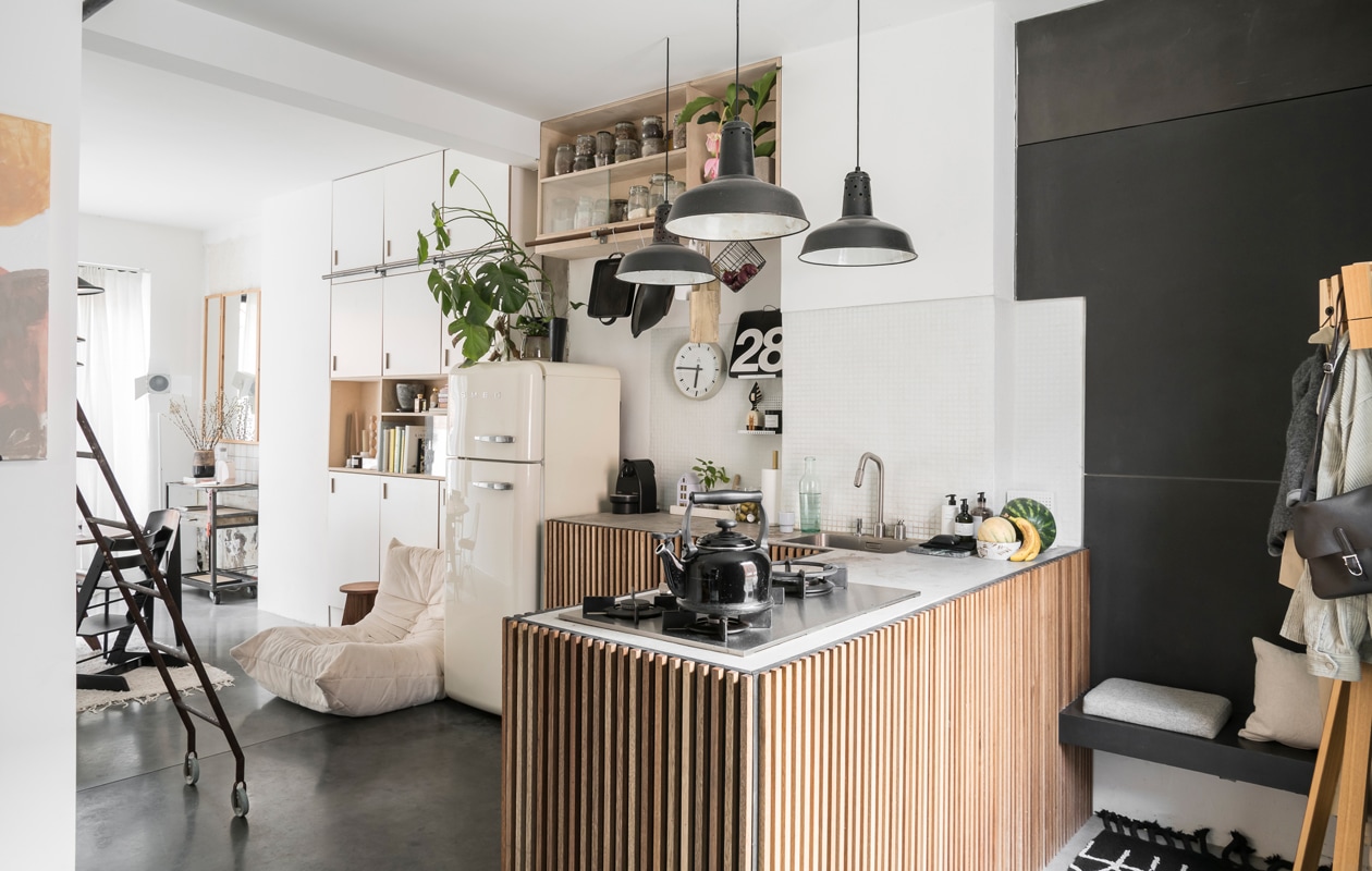 Naast de opnieuw gestoffeerde Togo fauteuil van Ligne Roset staat een kruk van Wøti, Williams eigen label. Koelkast Smeg, vintage klok van Pragotron gekocht bij Blom &amp; Blom. De keuken die William maakte is een hit op Pinterest. Het werkblad is van beton, de kastdeuren van zwarte mdf met slaglatten in meranti-hout. Lampen van een brocantemarkt in Frankrijk. vtwonen 2-2020 | styling &amp; fotografie Jonah Samyn