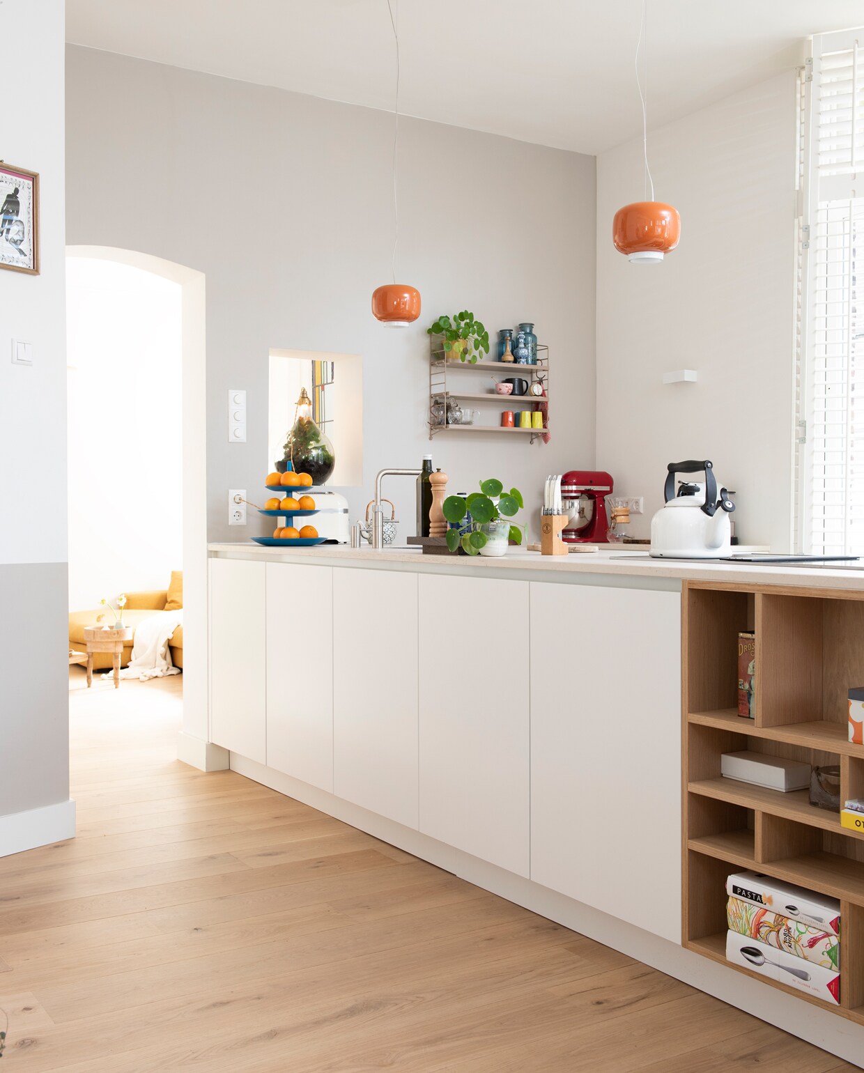 De keuken is een eigen ontwerp, uitgevoerd door Bears Design. Hanglampen Foscarini Chouchin Mini via MisterDesign. Wandrek String. Glazen lamp met ecosysteem gemaakt door Heleens collega Jimme. Theepot meegenomen uit Vietnam door Heleens dochters. Etagère Koziol. Pepermolen Peugeot. Messenblok Laguiole. Rode keukenmachine KitchenAid. Koffiemachine Nespresso. Fluitketel Le Creuset. Wandspotje Hill Lichtstudio. Gebloemd blikje Orla Kiely.