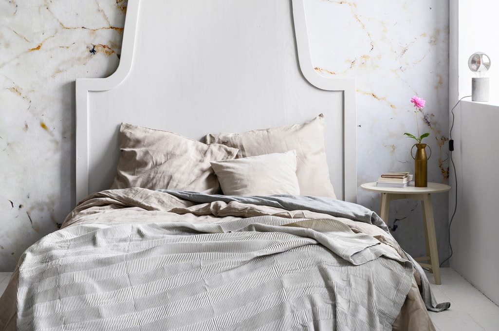 Fotobehang Milano met marmerprint, 300×300 cm, per rol € 149,- (karwei.nl). Bed-achterwand, 200×160 cm, prijs op aanvraag (com-anders.nl). Grijs-blauw plaid Vägmallä, 120×160 cm € 14,95, lichtbruin bedlinnen Puderviva, 240×220/60×70 cm € 79,95, bijzettafels Kragsta, 51×49 cm (hxØ) en 45×35 cm (hxØ) set van 2 € 79,95 (ikea.nl). Grijs flanellen bedlinnen vanaf € 17,50, hoeslaken Hotel vanaf € 18,- (hema.nl). Vaas van Bloomingville € 35,- (vtwonen.nl). Tafellamp Charis € 17 (kwantum.nl). Canvas Miss Susanna Gardiner, 25×30 cm € 45,- (werkaandemuur.nl). Overig privébezit. vtwonen 03-2020 | Styling Marianne Luning | Fotografie Stan Koolen | Assistentie Niels Kist en Roos van Bruggen