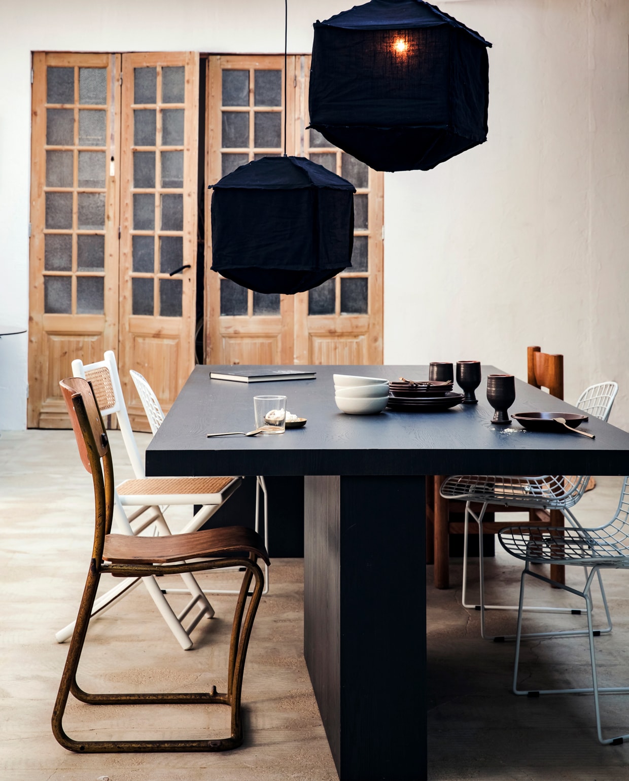 Hanglamp Titan van katoen, zwart (ook in wit), 40×60 cm (hxØ), 60×50 cm (hxØ), ook in 50×40 cm (hxØ). M.m.v. com-anders.nl (stoel links voor), ikea.nl (glaswerk), cocooncollectables.nl (tafel, overige stoelen, servies).