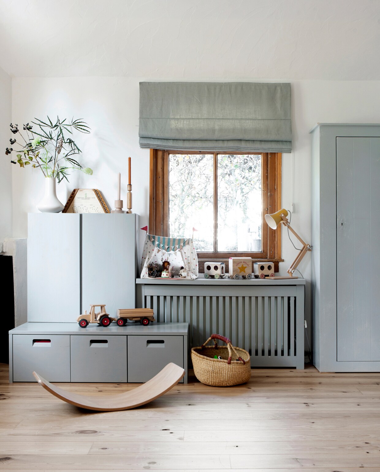 Kastje Ivar Ikea. Ladenbankje van vtwonen. Radiatorombouw Cando, geschilderd in de kleur van het ladenbankje. Vouwgordijn komt uit vorige huis. Lampje M.OSS Design. Circus Maileg. Tractor Fagus. Wobbel van Wobbel. Mand Dille &amp; Kamille. Kast rechts Timzowood Living. vtwonen 13-2019 | fotografie Jeltje Fotografie