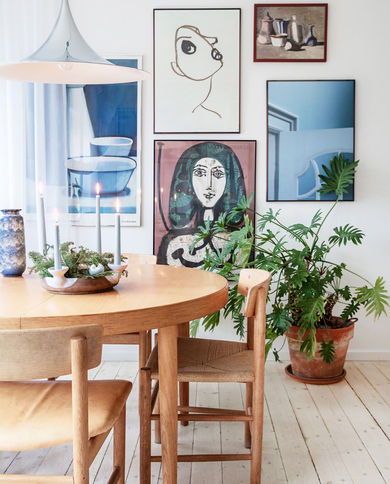 De tafel en stoelen van Børge Mogensen zijn vintage. Lamp van Gubi. Aan de muur posters van tentoonstellingen, een schilderij van een vlooienmarkt en een poster van Kristina Dam. Ook de bustes zijn rommelmarktvondsten. Kerstkrans zelfgemaakt en opgehangen aan een leren band, die past bij de kleuren en materialen van de eetkamer. vtwonen 13-2019 | styling Rikke Graff Juel | fotografie Christina Kayser O.