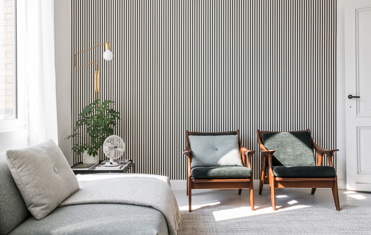 Het streepjesbehang is van Ferm Living, de vintage fauteuils met groene kussens vonden Sofie en Yannick bij Nome Furniture. De goudkleurige leeslamp is van House Doctor. vtwonen 13-2019 | styling &amp; fotografie Jonah Samyn