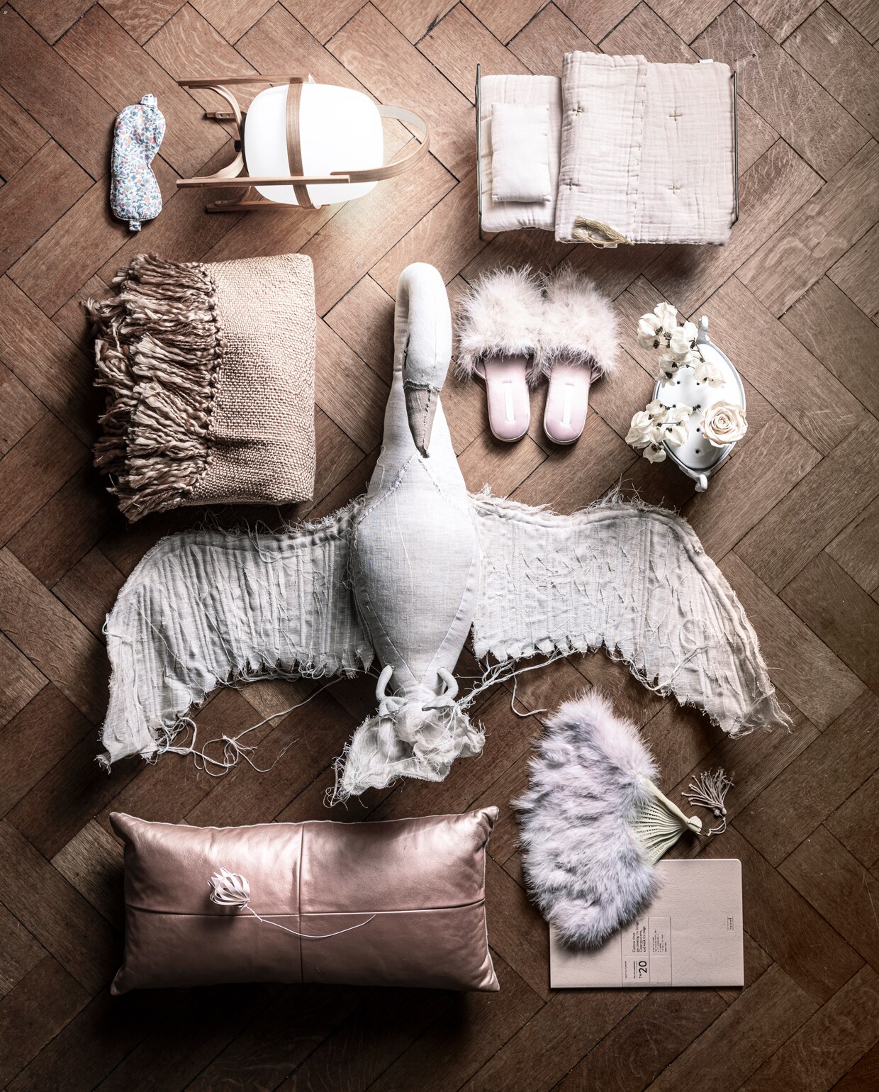 Oogkapje met lavendelgeur, plaid, witte vaas met zwanenhoofd (maisonnl.com). Lampje op batterij, papieren bloem, zalmkleurige planner (letoile.store). Zalmkleurig kinderbedje, beige zwaan voor op de wand (archive-store.nl). Sloffen met veren (zarahome.com). Glimmend zalmkleurig kussen (homestede.nl). Waaier privébezit.