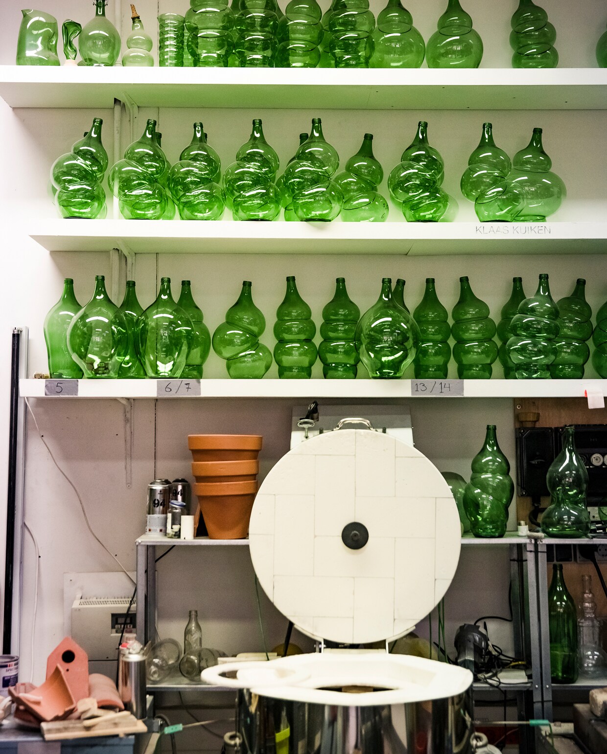 Begon Klaas met één tweedehands oven om de flessen mee te maken, inmiddels heeft hij er vier. Plus zijn meest recente aanschaf: een glanzend metalen keramiekoven waarin hij volop experimenteert met aardewerk. Klaas deelt het oude textiellaboratorium met elf andere creatieven, van architecten tot interactiondesigners. Er is een ‘vieze werkplaats’ met allerlei bankwerkmachines, een stofvrije kamer met een lasergestuurde snijmachine en een semiprofessionele fotostudio.