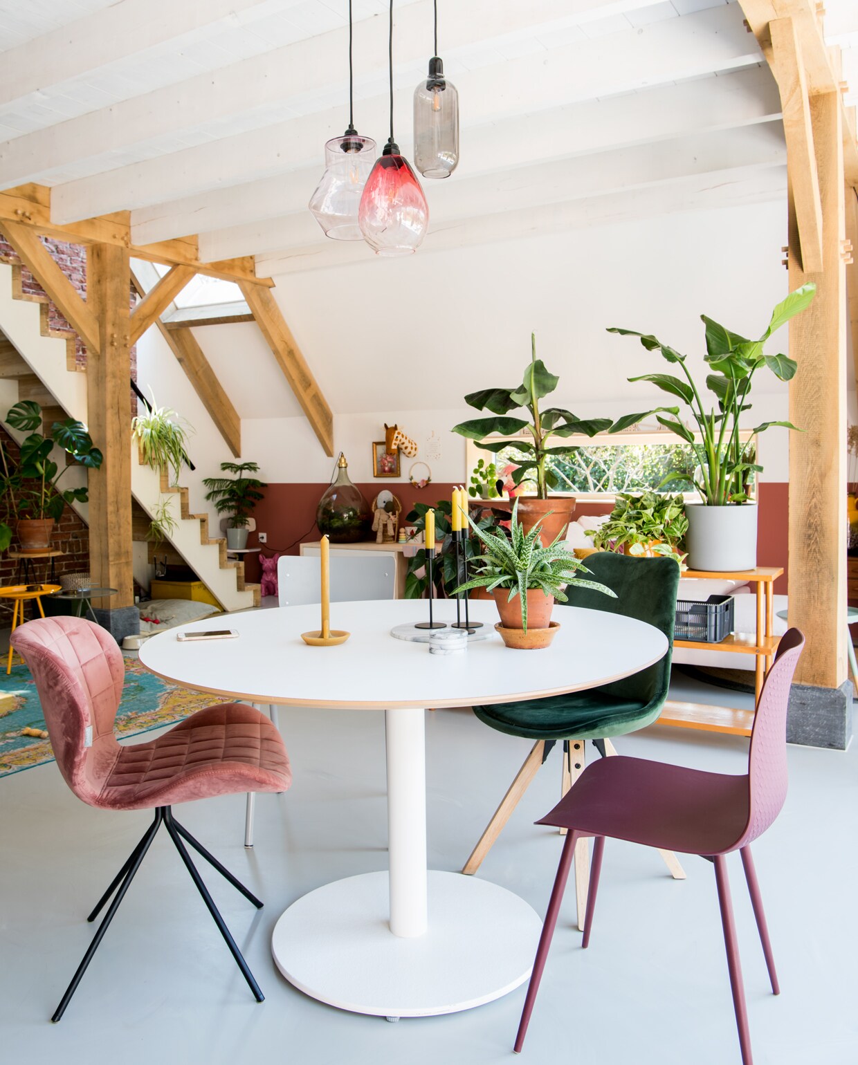 Hanglampen van made.com en Normann Copenhagen, paars stoeltje en groene stoel uit de vtwonen collectie, roze stoel van Zuiver. De vloer is een PU-gietvloer door de lokale firma Altach in twee kleuren gegoten waardoor een licht gemarmerd effect ontstaat.