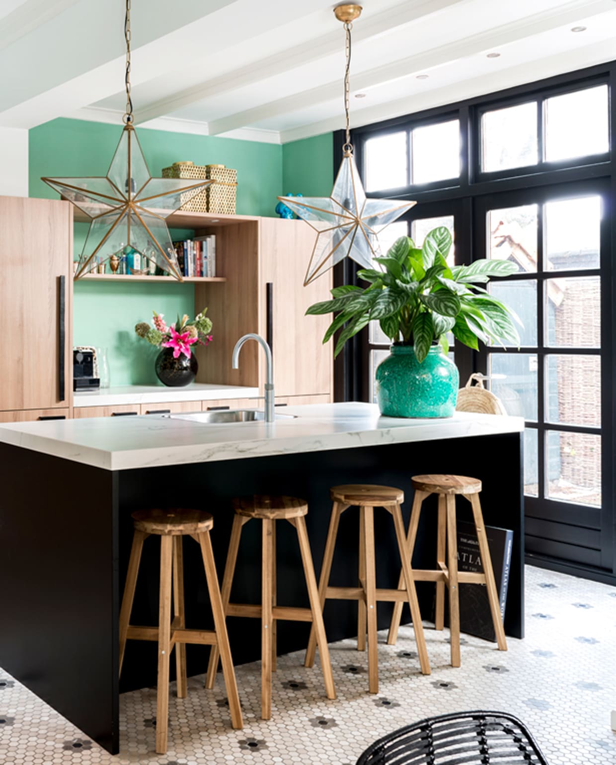 Keuken van Piet Boon. Stervormige lamp van Sissy-Boy. Plantenpot Mica Decorations. Vloertegels van designtegels.nl. Krukjes Ikea. Ananas links op het aanrecht komt uit Parijs, evenals de windlichten boven op de keukenkast, verkrijgbaar bij Studio Sophie. Muurverf kleur Arsenic van Farrow &amp; Ball. vtwonen special binnenkijken 12-2019 | styling Lindividu | fotografie Stan Koolen, CocoFeatures