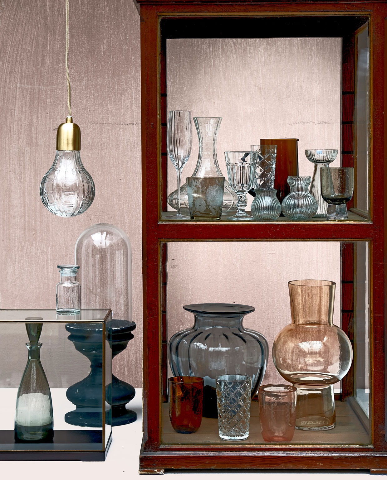 Verf achterwand Soft Clay van vtwonen (karwei.nl). Vitrinekastje (burbri.nl). Hanglamp, apothekerspot, stolp op voet (weldaad.com). Kleine vitrine (hkliving.nl). Karaf (neeflouis.nl). Op bovenste plank v.l.n.r.: geribbeld champagneglas (weldaad.com), bruin met bloem, karaf (polspotten.nl), glas op pootje, champagneglas Flimra met wieberpatroon (ikea.com), bruine karaf (householdhardware.nl), drie geribbelde bolvaasjes, hoog en laag, (weldaad.com), glas met bubbel op voet (polspotten.nl). Op onderste plank: grijze geribbelde vaas, glas met wieberpatroon (ikea.com), bruine vaas met bol in het midden (hkliving.nl), bruin glas en oranje glas (weldaad.com). JA | vtwonen 12-2019 | Styling Fietje Bruijn | Fotografie Dennis Brandsma, Frank Brandwijk