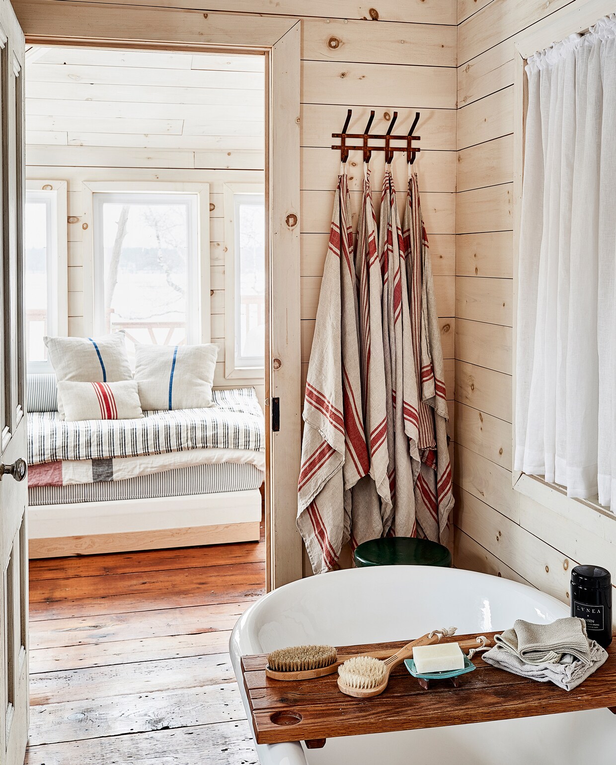 Het vrijstaande bad staat achter een houten wand waaraan de douche bevestigd is én die privacy en beschutting biedt. Handdoeken van Kokito.
