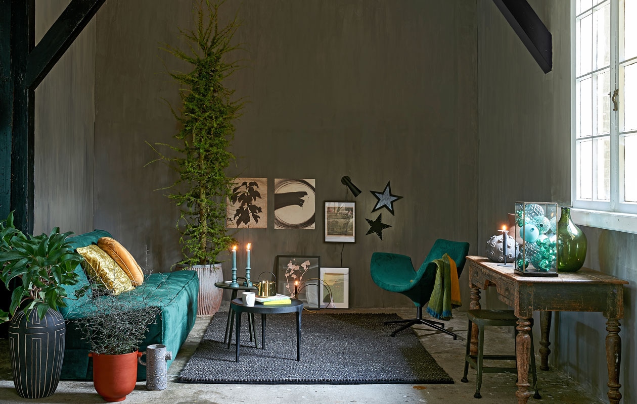 Bank Cluster van vtwonen. Zwart tafeltje van Loods 5 Design, tafeltje met handvat van Loods 5 Design, fauteuil van Loods 5 Design, groen-gele sjaal, kussen rond, kussen vierkant (loods5.nl). Hoge vaas, zwart-wit grafisch, rode pot, kan, wandlampje, goudkleurige kandelaar cirkelvormig, zwarte vaas (housedoctor.dk). Zinken pot, antiek tafeltje, groene fles (weldaad.com). Vloerkleed Hjorthede, 170×240 cm, beeld, lijsten (ikea.nl). Glazen stolp/vitrinekastje (hkliving.nl). Diverse groene kerstballen (rivieramaison.nl). Goudkleurige theepot (hkliving.nl). Sterren zelfgemaakt. Kruk, terracotta vaas en mok privébezit.
