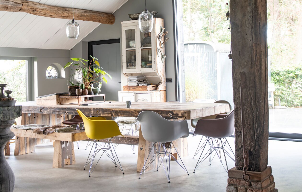Voor de robuuste, vier meter lange eettafel en de bank gebruikte de timmerman oude, onbewerkte grenen balken. Stoelen in Eames stijl. Hanglampen It's about RoMi. Buffetkast Combitex. De tinten Mouse (wand) en Salt (plafond) komen uit de verfcollectie van Stapelgoed. vtwonen 11-2019 | styling Esther Loonstijn | fotografie Louis Lemaire