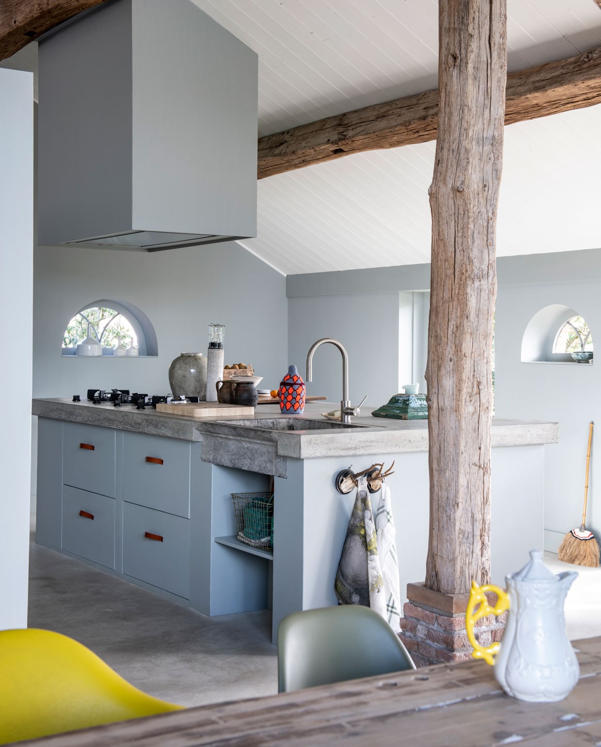 De keuken is geschilderd in de tinten Ash en Mouse van Stapelgoed. Het betonnen blad is ter plekke gestort op een gemetselde constructie. ‘We hechten aan details als de arduinen spoelbak, de geweivormige ophangpunten en de leren ladekastgrepen van Handles and More.’ vtwonen 11-2019 | styling Esther Loonstijn | fotografie Louis Lemaire
