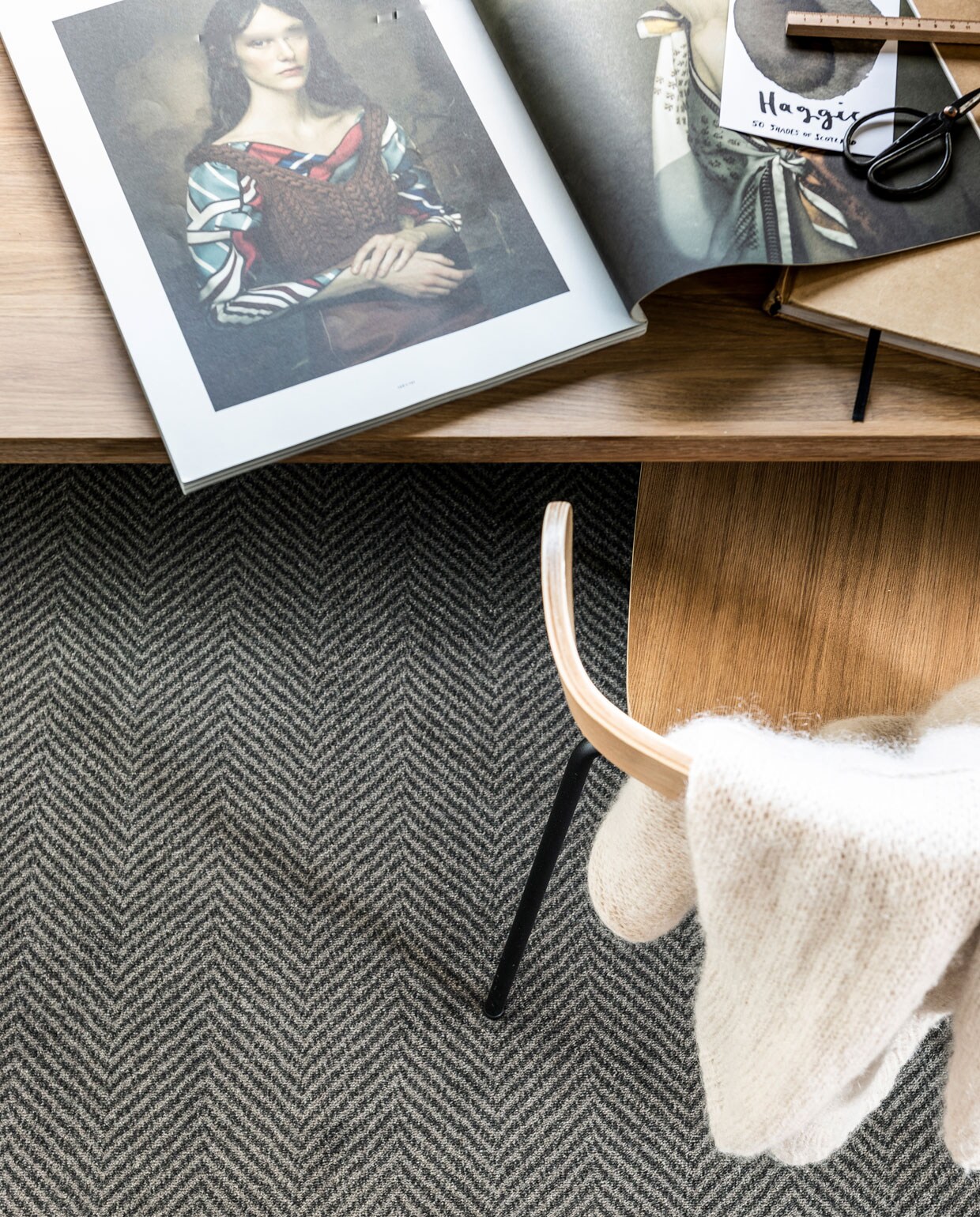 Tapijt Herringbone Mud Grey, ook in Zinc, 400 cm breed, vloerkleed op maat gemaakt met gefestonneerde rand 200×300 cm. M.m.v. vtwonen.nl/vtwonen-collectie (poef, fauteuil), bepurehome.com (houten stoel), hetkabinet.nl (zwart metalen dressoir), stories.com (vest).