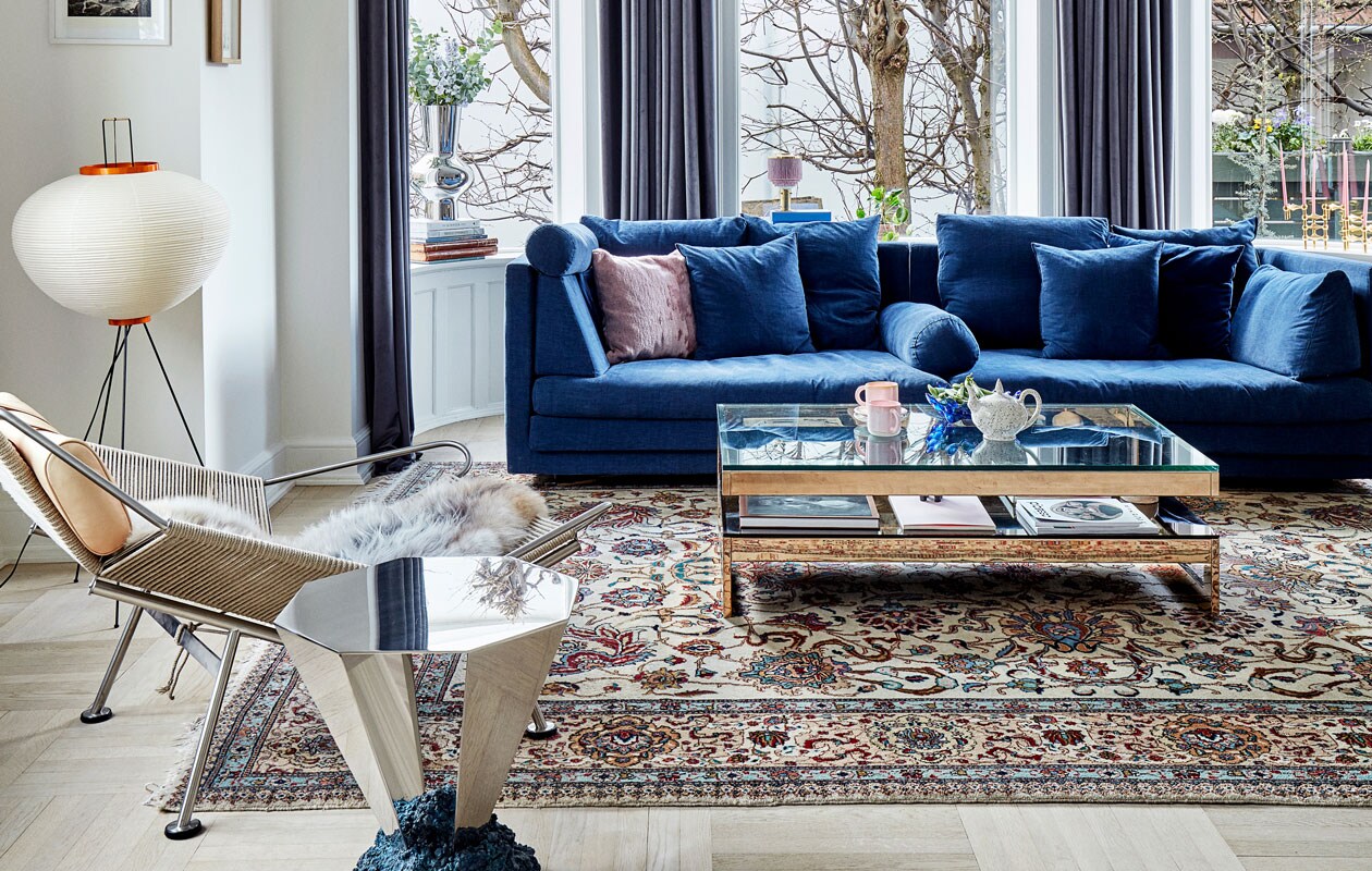 Designparadijs in de zithoek: de blauwe bank van het Deense label Eilersen wordt gecombineerd met de vintage Flagline Chair van Hans Wegner, de Diamant Table van Fos, een vintage koffietafel van Belgo Chrom, lamp Sputnik van Paul de Haan en rijstlamp Akari van Isamu Noguchi. Het vloerkleed is een erfstuk.