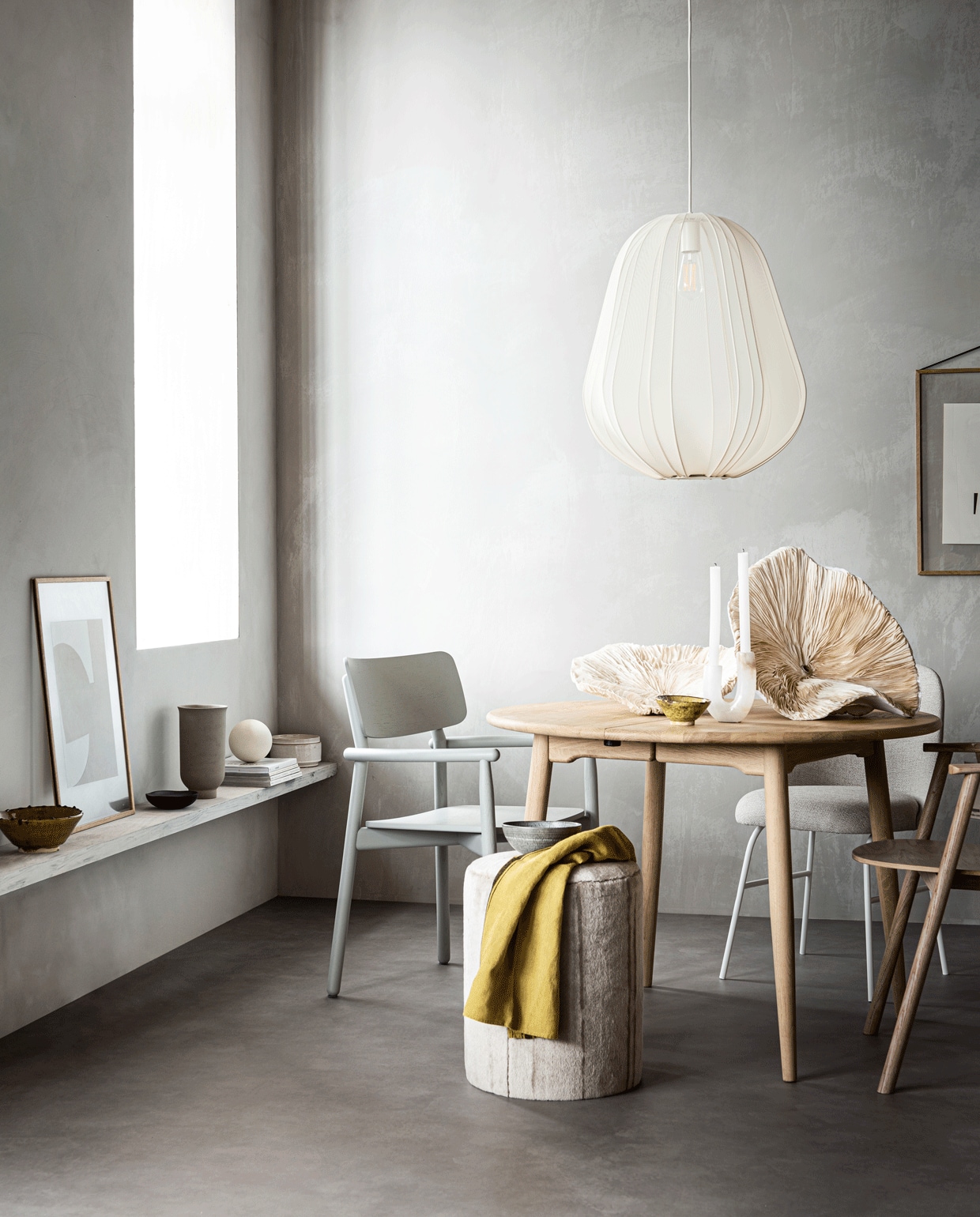 Muurverf kleur North,(bauwerkcolour.com). Vloer Novilon kleur Beton van vtwonen, 200 cm of 400 cm breed, exclusief installeren (vtwonen.nl/vtwonen-collectie). Ronde eikenhouten tafel (coosdewitwonen.nl). Zachtgrijze houten eetkamerstoel (letoile.store). Gestoffeerde eetkamerstoel met witte poten Aleta van Viccarbe (designtales.nl). Witgelakte eikenhouten eetkamerstoel, hanglamp 60×53,3 cm (hxØ) (bolia.com). Poef grijze craquelé schaal met witte streep (covanderhorst.nl). Kunstobjecten in zwamvorm gemaakt van moerbeipapier,(elsavisser.com). Vaalgele keramieken schaal, marmeren kandelaar met kleurschakeringen (loods5.nl). Vaalgele theedoek (maisonnl.com). Eikenhouten lijst (letoile.store). Poster Deconstructed no. 34, 29,7×42 cm (ateliercphshop.dk). Op de plank: vaalgele keramieken schaal, zandkleurige pot met deksel (loods5.nl). Poster Object blanc no. 25, 40×30 cm (ateliercphshop.dk). Eikenhouten lijst (letoile.store). Zwart houten schaaltje (loods5.nl). Grijze vaas van Menu (designtales.nl). Witte bol (covanderhorst.nl). Overig privébezit.