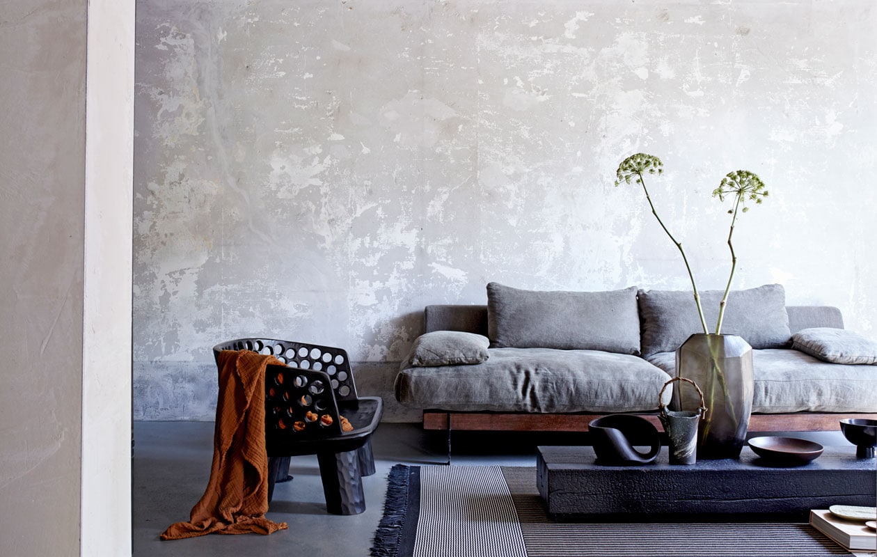 Zwarte houten fauteuil, zwart object op salontafel (badenbaden.nl). Bank Ciel met linnen bekleding van l’Authentique, 220x100x70 cm (bxdxh) (deruverfenbehang.nl). Vloerkleed grotendeels gemaakt van papier, 240×170 cm (lxb) (vloerkledenwinkel.nl). Roestkleurige plaid, zwarte kom op voet (hm.com). Salontafel van zwart gebrand hout, glazen vaas (covanderhorst.nl). Keramieken kan met bamboe handvat (japansewinkeltje.nl). Ovaal zandkleurig keramieken bord (desimonewayland.com). Houten schotel (restored.nl). Overig privébezit.