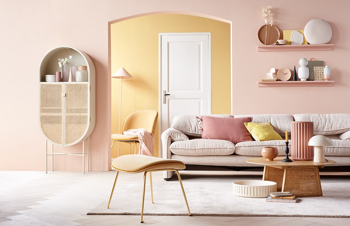 Verf op de voorste wand Vla, achterwand Mosterd van HistorOne (deruverfenbehang.nl). Parket visgraat eiken wit geolied van vtwonen, breedte plank 15 cm (karwei.nl). Kast, roze vloerlamp, roze plaid, salontafel, wit ornament hoofd (hkliving.nl). Voorraadpot van keramiek met deksel, donkerroze vaasje, blank houten kegel, roze kussen met strikjes, zwarte houten kegel (loods5.nl). Zachtroze glazen vaas in organische vorm, miniatuur Vitra designstoel, vaas met bol, spiegel in zachtroze platte ronde vaas (loods5.nl/design). Beige vaas met roze hals, tafellamp met houten poot (coosdewitwonen.nl). Zachtgele fluwelen fauteuil met voetenbank, witte xl schaal van keramiek, roze xl vaas van kveramiek (mobilia.nl). Bank (dekasstoor.nl). Geel fluwelen kussen (hm.com). Vloerkleed in Nougat Rose (vloerkledenwinkel.nl). Roze bolvaas, terra dienblad, gele snijplank (vtwonen.nl). Zwarte metalen kandelaar (paviljoennoord.com). Notitieboeken, grijze leren portemonnee, witte kom met roze strepen (klevering.nl). Klok van keramiek, schriften, wit vaasje met roze onderkant (letoile.store). Overig privébezit. vtwonen 06-2019 | Styling Danielle Verheul | Fotograaf Petra Steenkamer