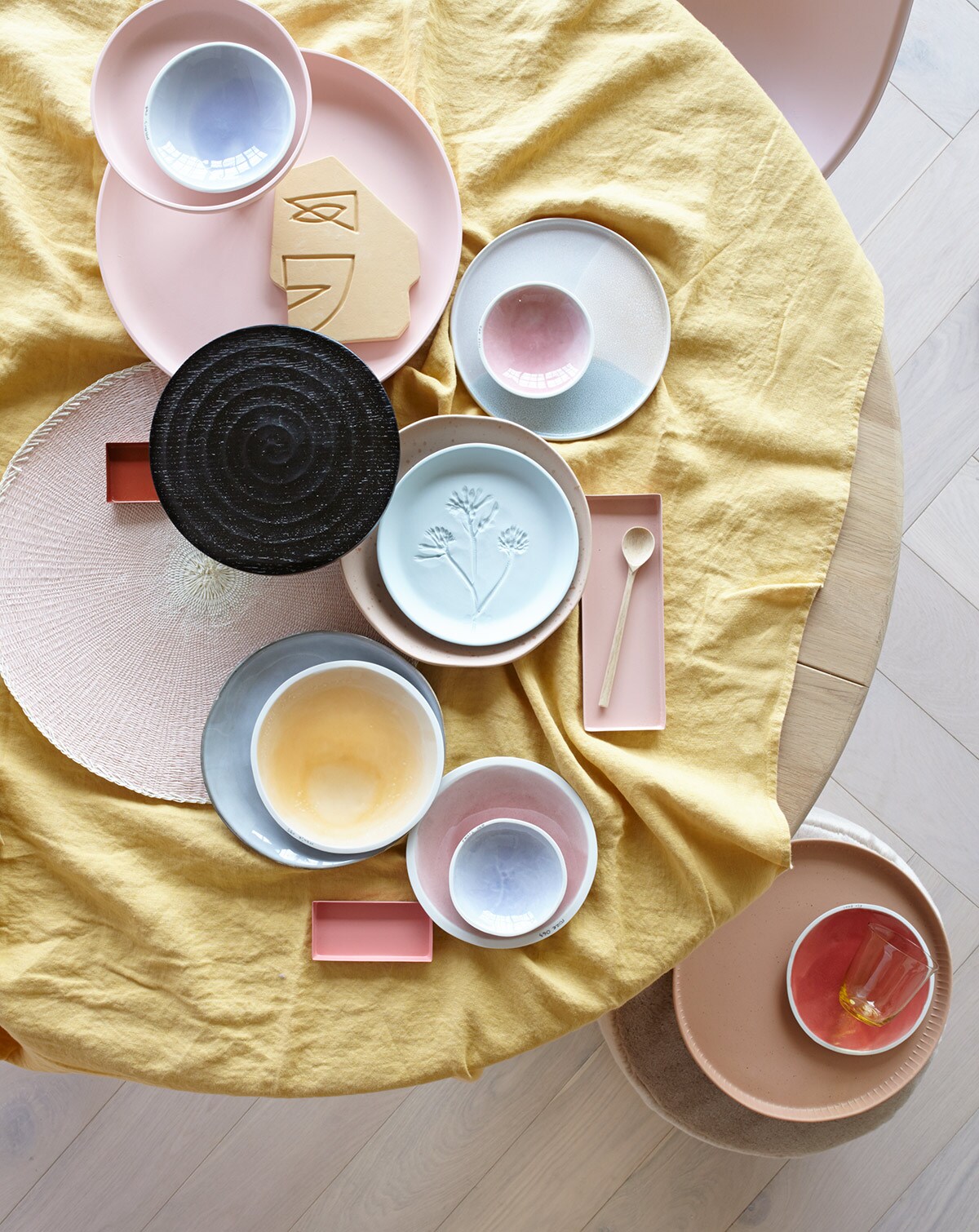Parket visgraat eiken wit geolied van vtwonen (karwei.nl). Ronde eikenhouten eettafel, roze eetkamerstoel (coosdewitwonen.nl). Geel linnen tafelkleed (letoile.store). Roze etagère (loods5.nl/design). Schaaltjes XS in blauw en roze, S in blauw, M in geel, roze en rood (studioharmenelke.nl). Ornament gezicht, rond bord met opstaande rand, rond terra dienblad (hkliving.nl). Zwarte houten etagère (paviljoennoord.com). Roze placemat (klevering.nl). Niet perfect rond bord met spikkeltjes, vergrijsd blauw bord (loods5.nl). Lichtblauw bord van keramiek met bloemprint (letoile.store). Rechthoekige schaaltjes in verschillende tinten roze, geel glas (hm.com). Houten lepel (restored.nl). Roze fluwelen poef (covanderhorst.nl). vtwonen 06-2019 | Styling Danielle Verheul | Fotograaf Petra Steenkamer