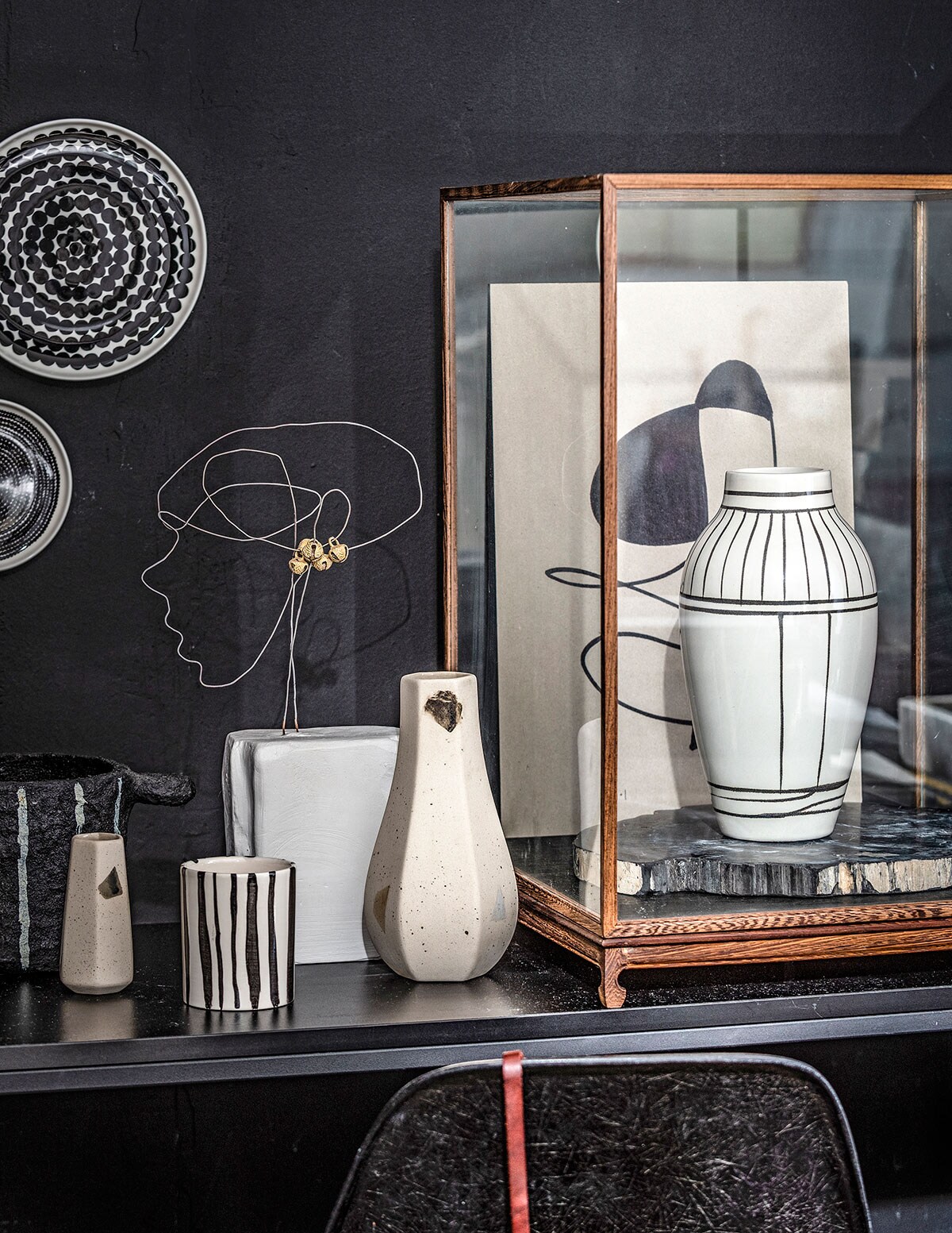 Keramieken masker naturel (studiosomee.com). Eiken lijst A2 (moebe.dk). Print van Loulou Avenue (loods5.nl). Kunstwerkprint van atelier CPH in eiken lijst van Moebe, kunstwerkprint van Marrit van Nattem in eiken lijst van Moebe (restored.nl). Borduurring Beads (housedoctor.com). Print Silhouette, print Stretch inclusief houten lijst en passe-partout, print Palms (mydeers.nl). Zwarte ronde tafel Copenhague (hayonlinewinkel.nl). Zwarte draadkruk Wire van Cees Braakman (pastoe.nl). Witte draadstoel Bertoia voor Knoll Studio (cocooncollectables.nl). Zwart potje met wit reliëfdessin (hm.com). Kookboek Chicken on Charcoal, kookboek Serious Cookbook, borden van Marimekko (klevering.nl). Keramieken mok met stip Ladybird, grijs linnen servetten set van 2 (ooh-noo.com). Witte mok Melting Mug van Arhoj (sixandsons.com). Lamp samengesteld uit emaillen witte lampenkap, katoenen snoer, koperen fitting (pantoufle-design.nl). Lijsten op de grond en zwarte stoel privébezit. Passe-partout voor kunst