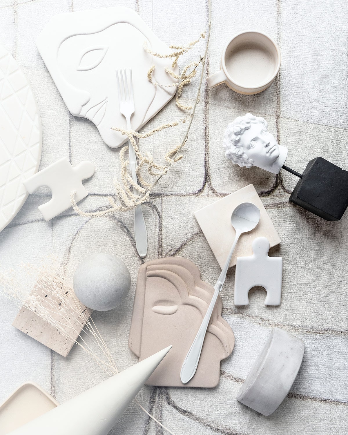 Behang (wallanddeco.com). Sierstuk maan, sierstuk ronde bal (101cph.com). Kegel, puzzelstukjes en stukjes steen, stenen schaal (covanderhorst.nl). Bestekset vierdelig (lisannevanzanten.nl). Droogtakjes (tuinvanjudith.wordpress.com). Gezichten in beige en wit van HK Living (wonenmetlef.nl). Kopje op zwarte sokkel (zarahome.com). Mok met oor (studiopansa.com).