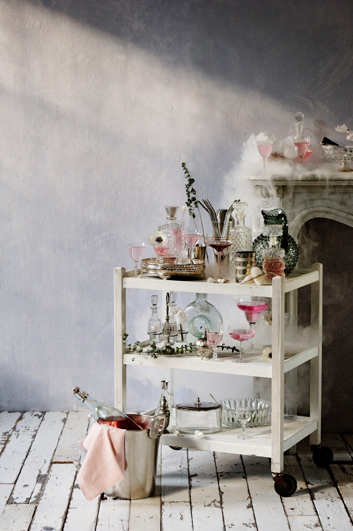 Muurverf lichtblauw kleur Iris, (bauwerk.com.au). Schouw van wit marmer (Jan van IJken). Bloemen en takken (judithslagter.nl). Witte trolley (Vroeger&amp;Toen). Wijnkoeler (PolsPotten). Ballen van karton, set van 2 (H&amp;M). Zilverkleurig dienblad (Zara). Zilverkleurige stalen rietjes (Dille&amp;Kamille). Lichtblauwe kan (Burbri Antiek). Karaffen, glazen trommel met zilverkleurige deksel, peper-en-zoutstelletje, klein zilverkleurig flesje (Vint Amersfoort). Blauwe glazen kan (artilleriet.se). Zilverkleurig glas (Maison NL). Limonaderecept van The Holy Kauw Company (theholykauw.nl) uit boek Limonade (Uitgeverij Snor). Glazen (kringloopwinkel). Roze servert privébezit. vtwonen 13-2018 | fotografie Brenda van Leeuwen | styling Liza Wassenaar