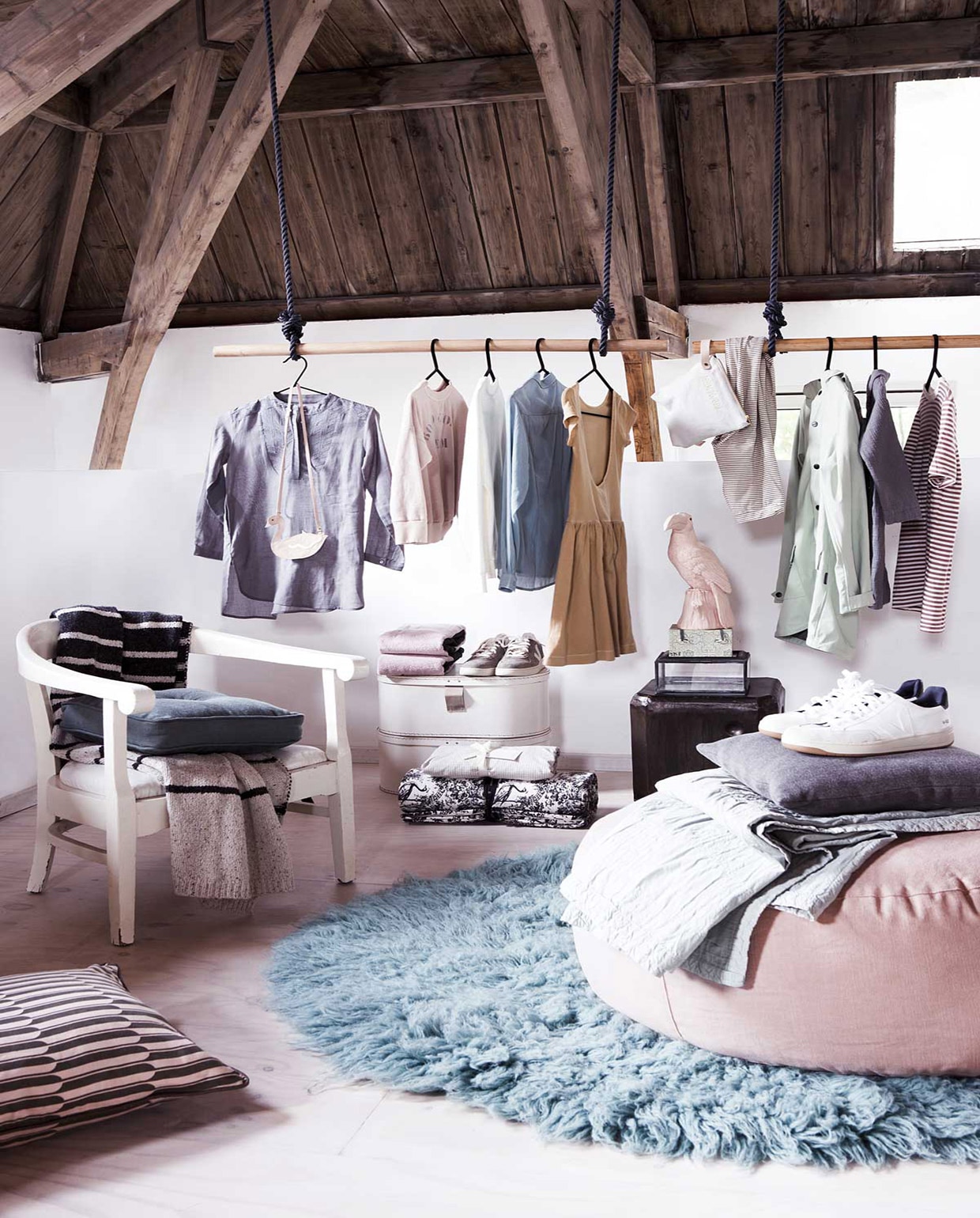Zwarte kledinghangers per 4 (). Grijze blouse, roze trui, witte trui, blauwe blouse, oranje jurk, tasje, legging met zwarte streep, lichtgroene jas, grijs jasje, zwart-wit gestreepte plaid, hoeslaken met vierkantjes dessin (). Tasje in zwaanvorm, grijze en witte schoenen (). Shirt met streep (). Handdoek (). Groen kussen op stoel, rond blauw kleed, roze poef (). Groen-roze geprint kussen van Ferm Living op de grond, groen plaid van Vestbjerg, grijs  van By Mölle, roze  van &amp;k amsterdam, zwart-witte  met opdruk van Day (). Glazen doosje (). Groen bakje bij een kringloopwinkel, overig privébezit. JA vtwonen 09-2018 | Fotografie Jeltje Fotografie | Styling Liza Wassenaar
