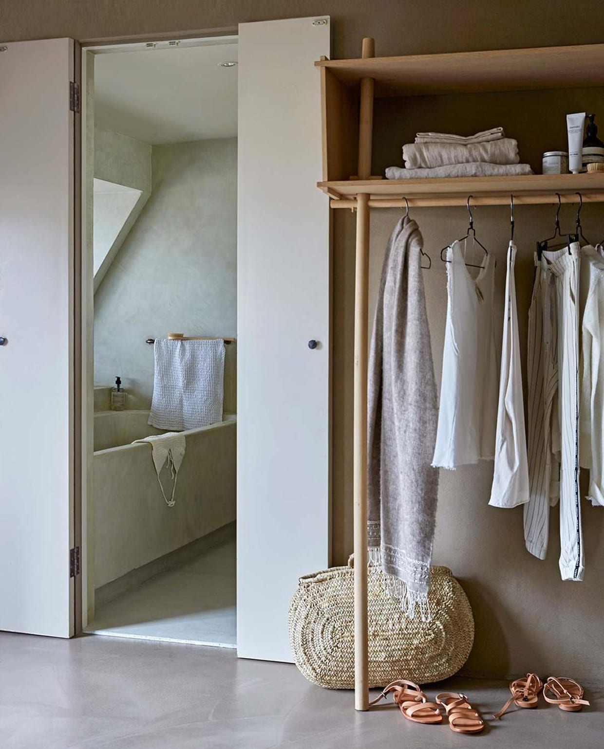 Vloer in beton ciré, bad in beton ciré (Pureconcept). Muurverf Buffalo (Tribe). Kledingkast (Woud). Linnen lakens (By Mölle). Witte handdoek (Ferm Living). Badproducten van Meraki, borstels van Meraki (vtwonen.nl). Kleding (10 Days). Gehaakte top, sandalen, wollen sjaal, rieten tas (Sukha Amsterdam).