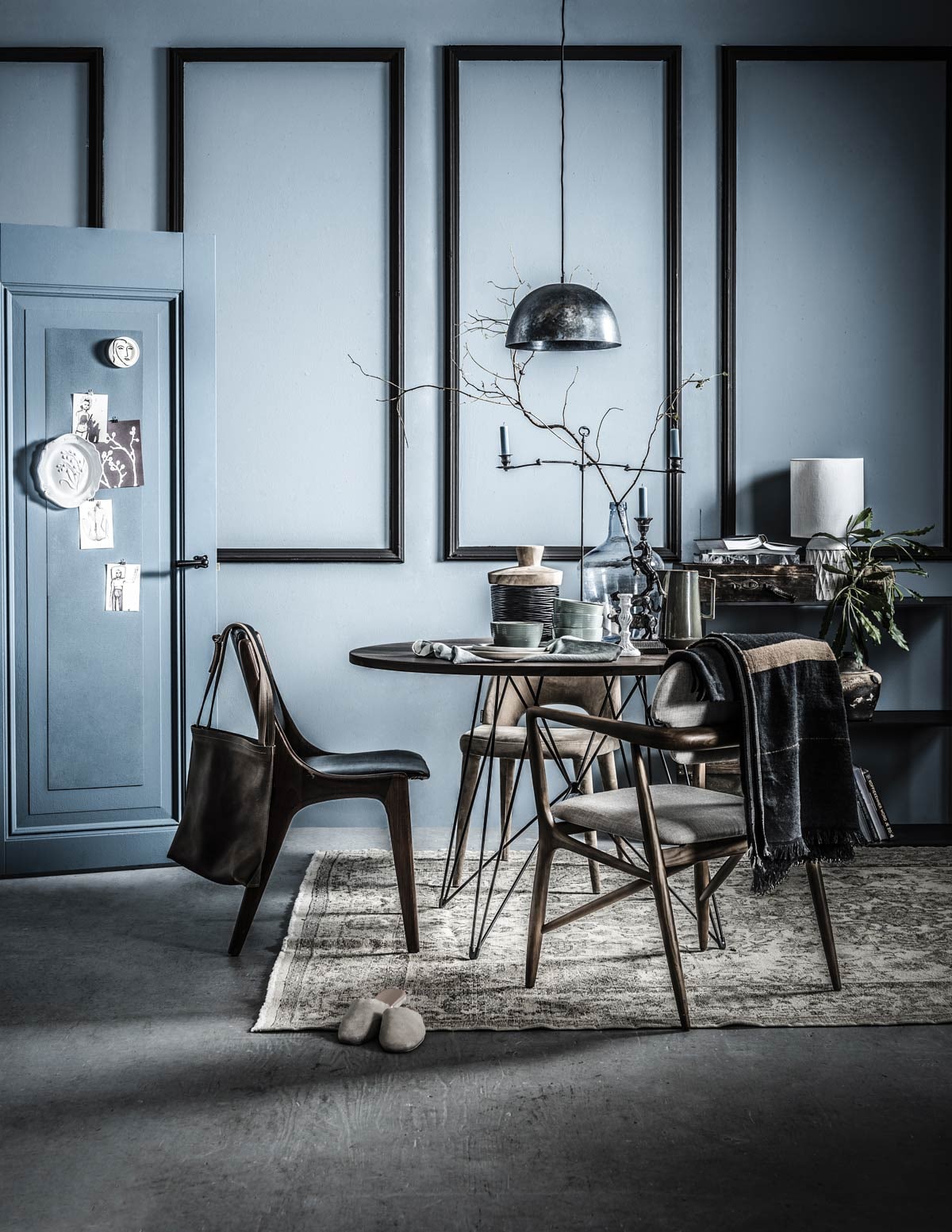 Muurverf Old Blue van vtwonen (). Verf op de deur Juniper Ash (). Kurk op deur (). Kaart met geschilderd model ( via Nicole Wegman). Bord met gezicht, blauwe bakjes met goudkleurige rand (). Wit bord met bloemenopdruk, witte kaarsenstandaard (). Leren tas van Philomijn (). Leren stoel in bruin met zwart (). Bruine sloffen (). Vintage vloerkleed (). Ronde tafel met stalen poten, zwarte pot met houten deksel, pot in kast, kast Twin Bookcase van By Lassen (). Stoel met houten leuning, stoel met gestoffeerde zitting en rug (). Plaid, linnen theedoek (). Blauwe stalen lamp (). Hoge kaarsenstandaard, groene kan, blauwe kaarsen, kandelaar met paard, witte tafellamp (). Blauwe glazen vaas, bruine houten koffer (). Boeken en kaarten privébezit.