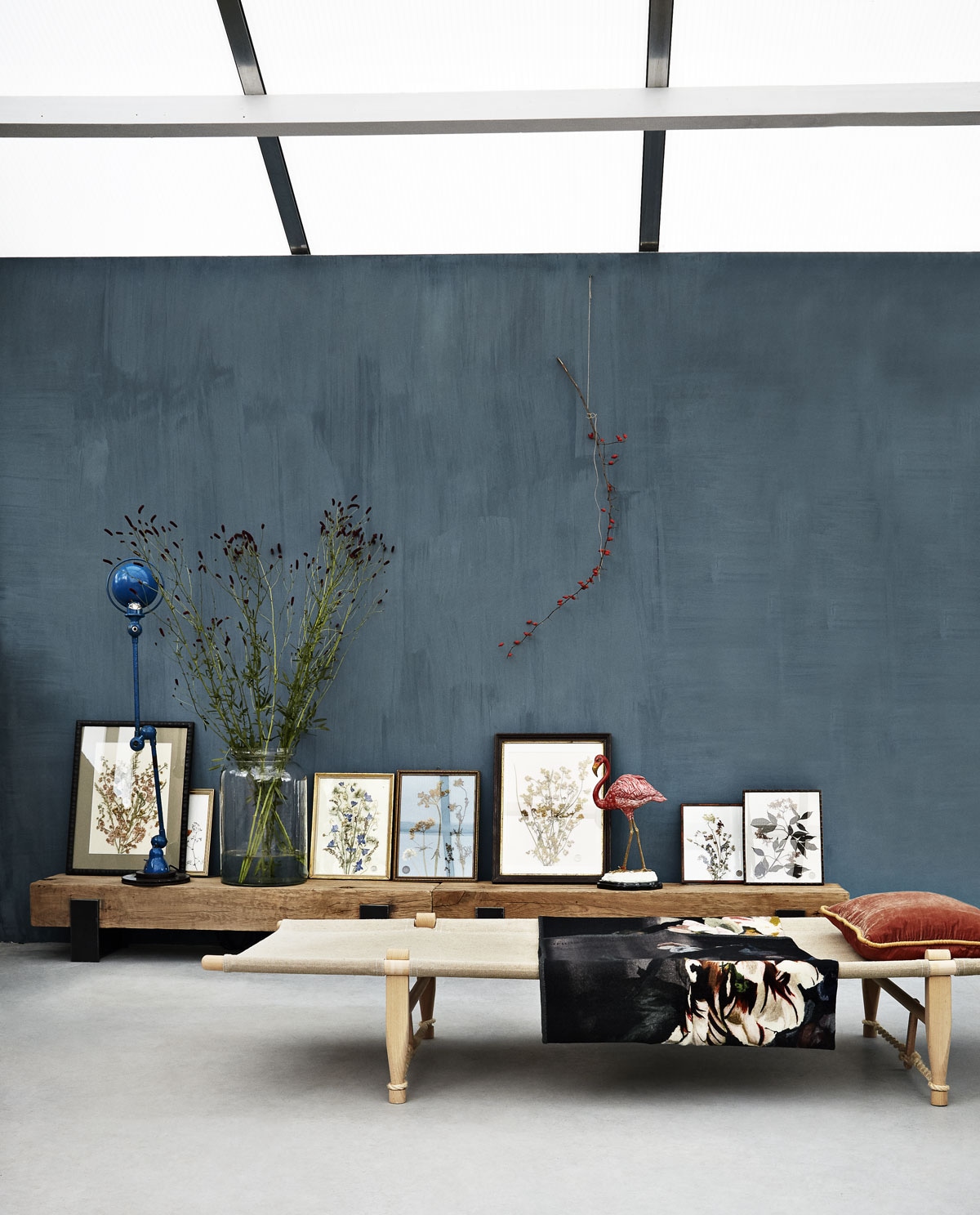 Muurverf kleur Tattoo (We Are Wow Makers). Tafel Saam van massief eikenhout en staal (boxworx.nl). Oude lijsten Frames of Hope gevuld met gedroogde bloemen en grassen uit Frankrijk (Field of Hope). Oude blauwe lamp van Jieldé (Brût Amsterdam). Vaas (Van Dijk &amp; Ko). Flamingo van keramiek en brons (MaisonNL). Veldbed van berkenhout en linnen/sisal (By Mölle). Kussen van fluweel van Madam Stoltz (deens.nl). Kleed van wol Delft Flower Noir van Designers Guild (Wilhelmine van Aerssen).